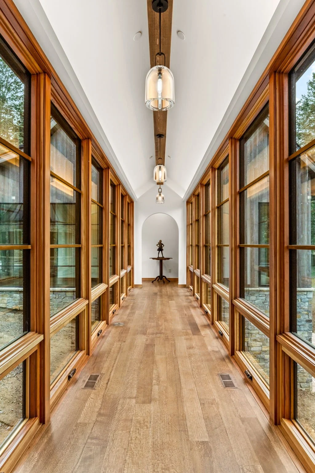 Hallway at the Cedar & Stone residence in Jefferson County, Colorado, with wood framing, glass panels, and natural light.