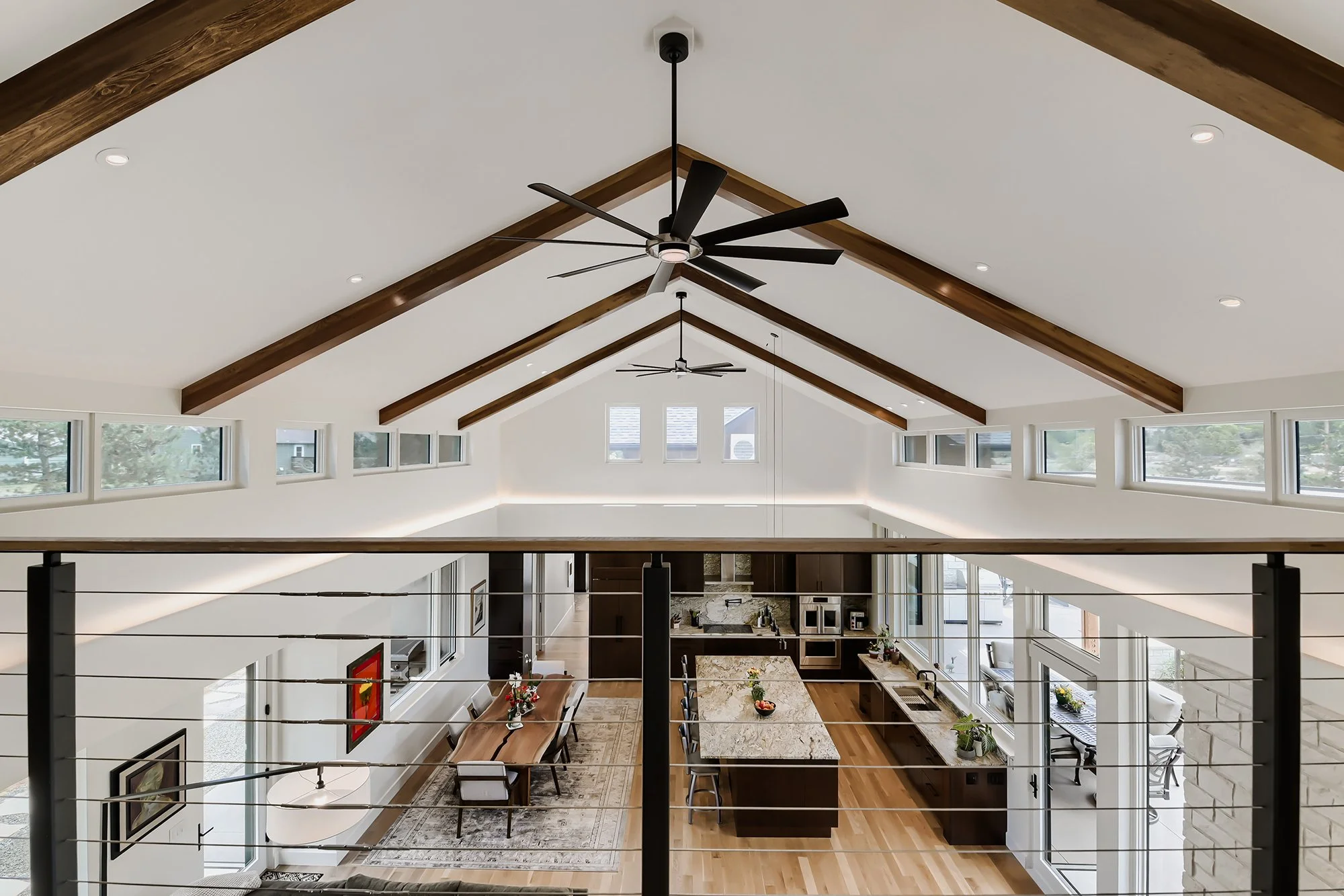 Modern open-concept living room with vaulted ceilings, fireplace, and warm wood flooring.