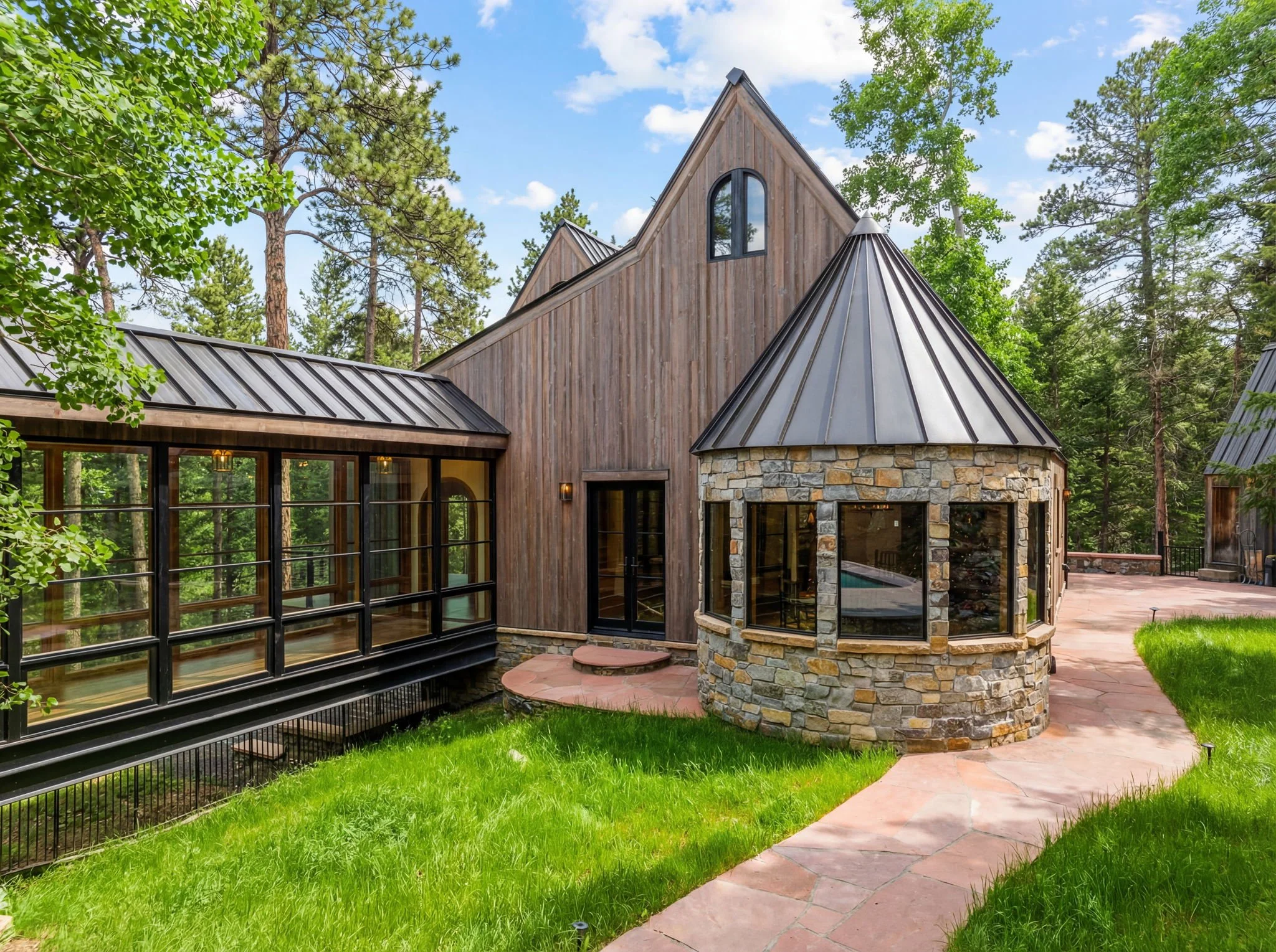Cedar & Stone residence in Jefferson County, Colorado, featuring cedar siding, stone turret, standing-seam metal roof, and glass corridor in wooded setting.
