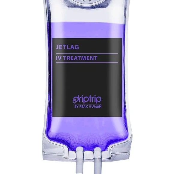 A clear IV drip bag filled with purple liquid, labeled 'Jetlag IV Treatment' from Driptrip by Peak Human.
