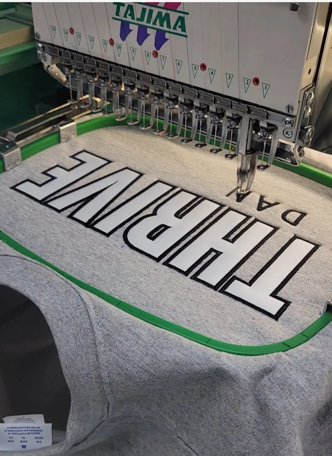 an embroidery machine putting a logo on a grey sweatshirt