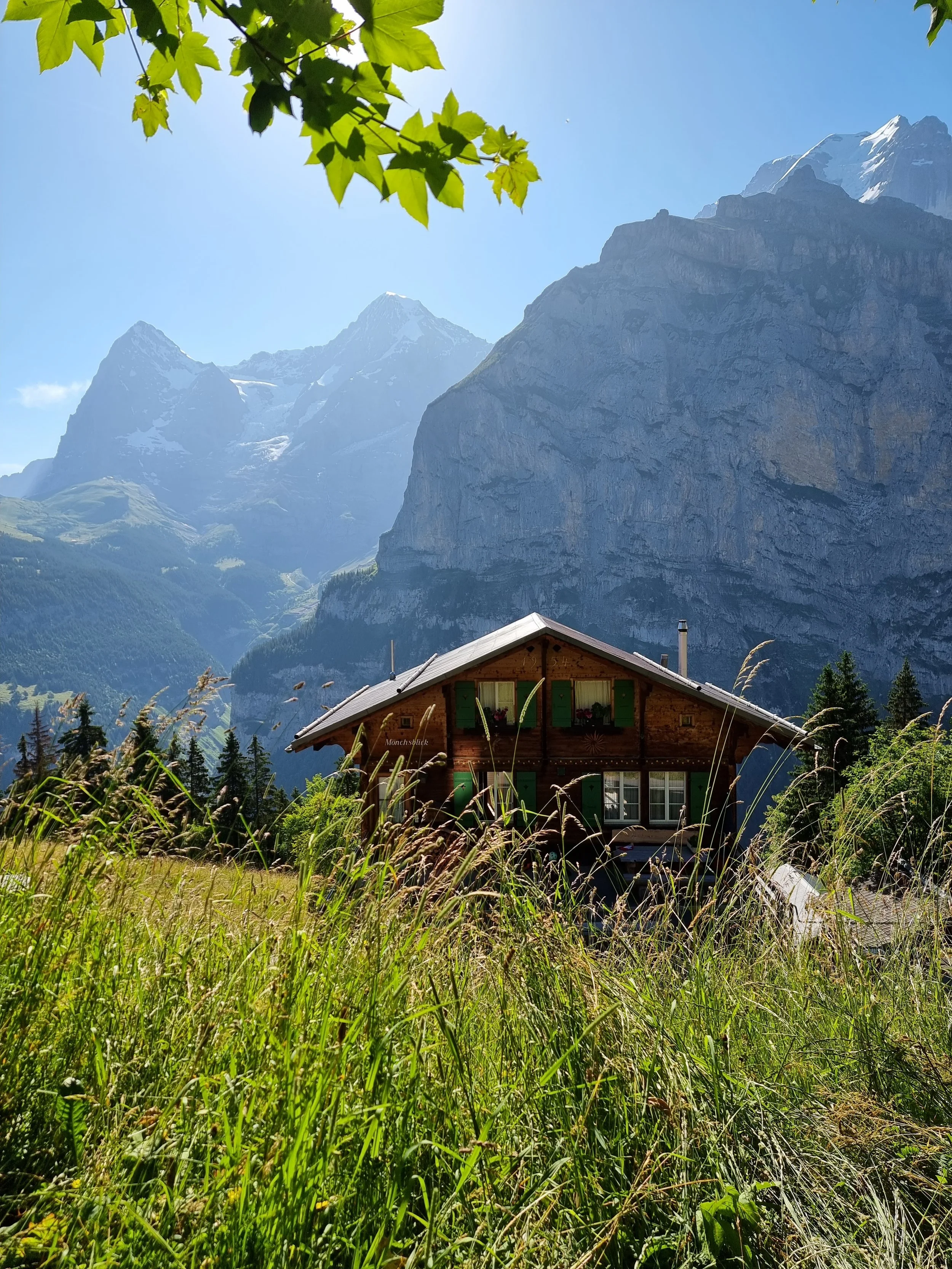 Two women sitting on grass and practicing yoga or meditation with mountains and clouds in the background.