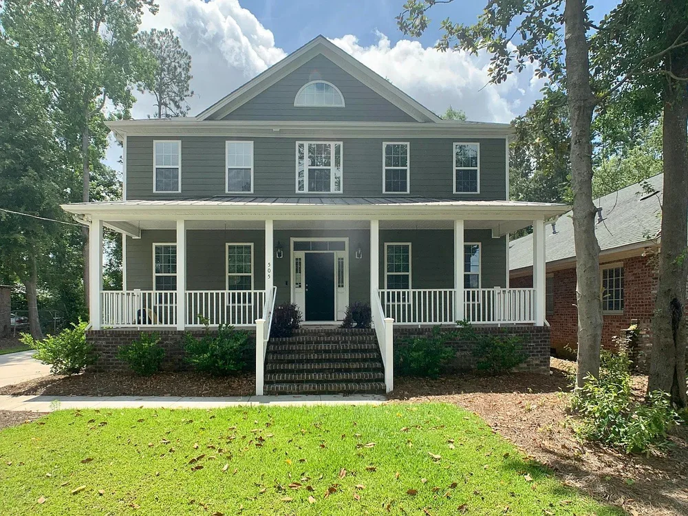 A two-story farmhouse with a full-width front porch