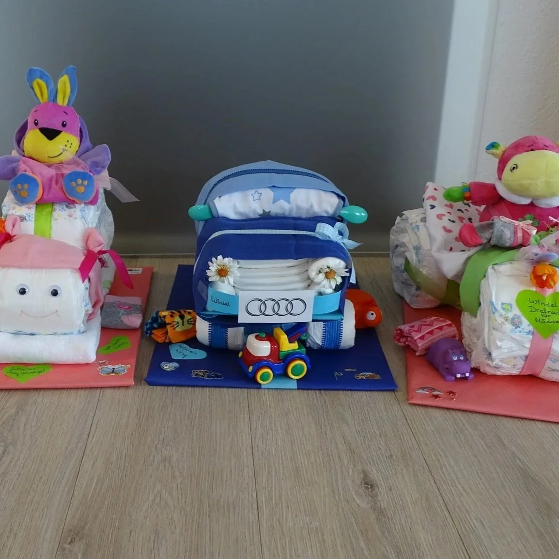 Süsse Geschenkpakete für Babys, umrahmt von Stofftieren und kleinen Spielsachen.