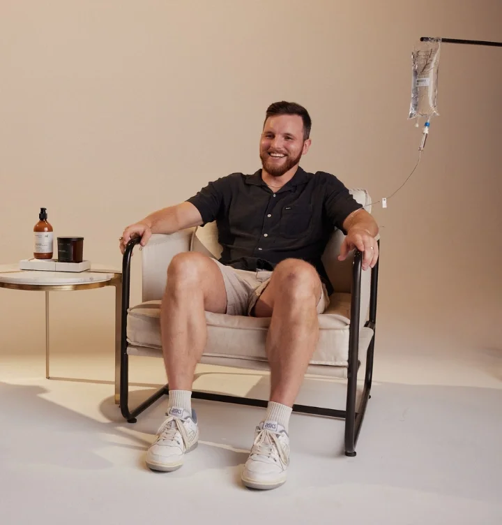 Man smiling while receiving IV NAD+ therapy in a lounge chair at FORMAT Fitness & Wellness in Fort Worth.