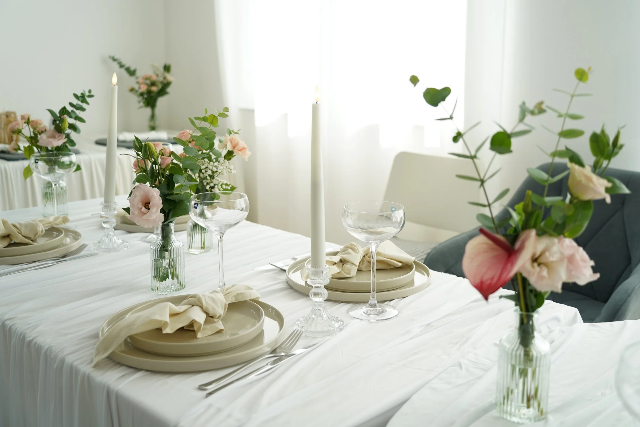Festlich gedeckter Esstisch mit Blumen, Kerzen und elegantem Geschirr in heller, natürlicher Beleuchtung.