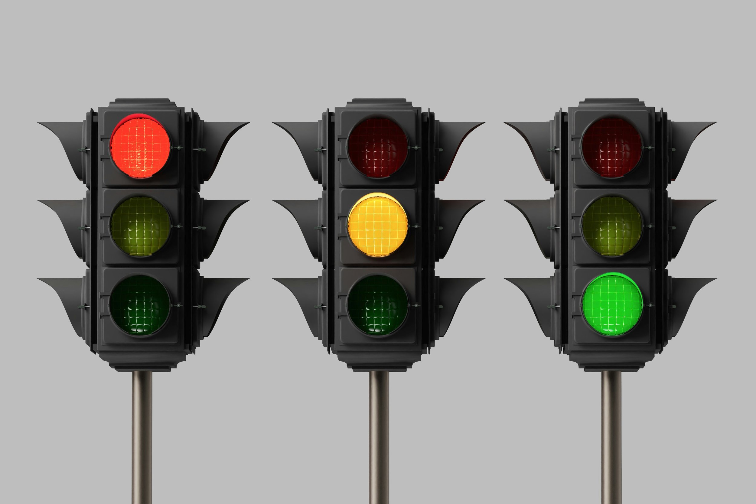 3 traffic lights side by side, each one with a green or yellow or red light glowing