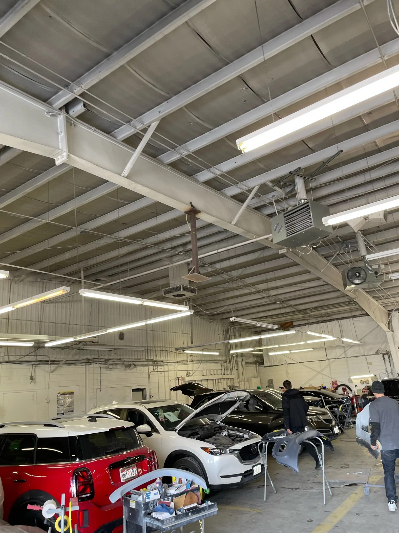 Auto repair shop with several cars being worked on and two people inspecting a black car