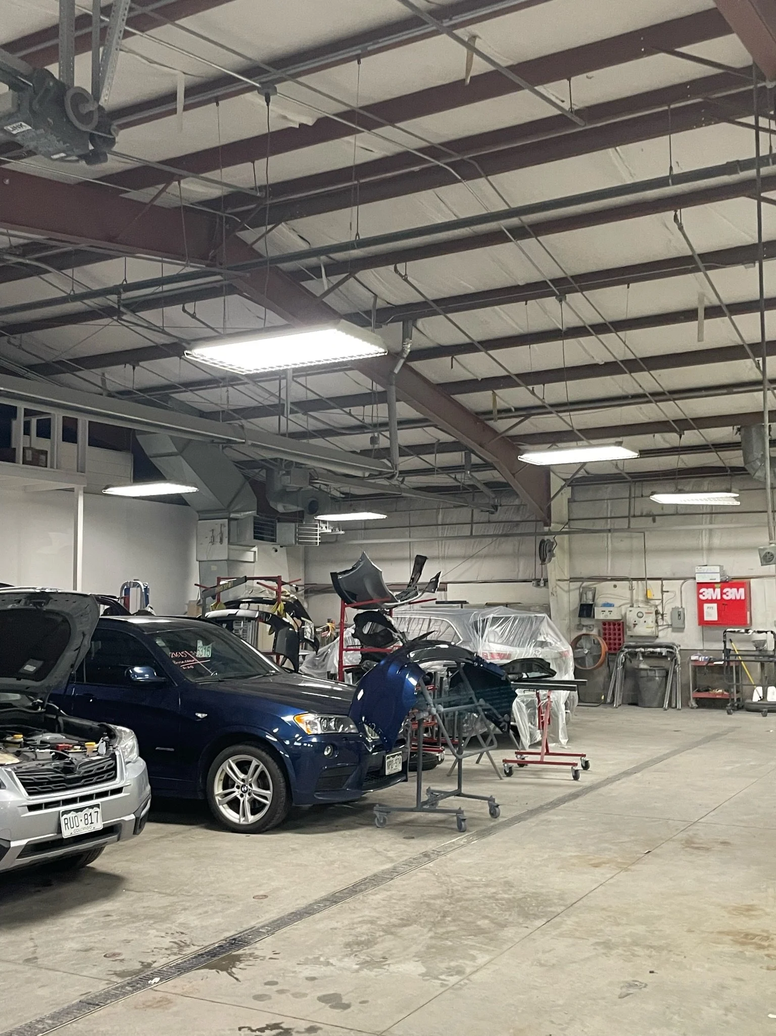 An automotive repair shop with cars, some disassembled, and equipment for vehicle repairs.