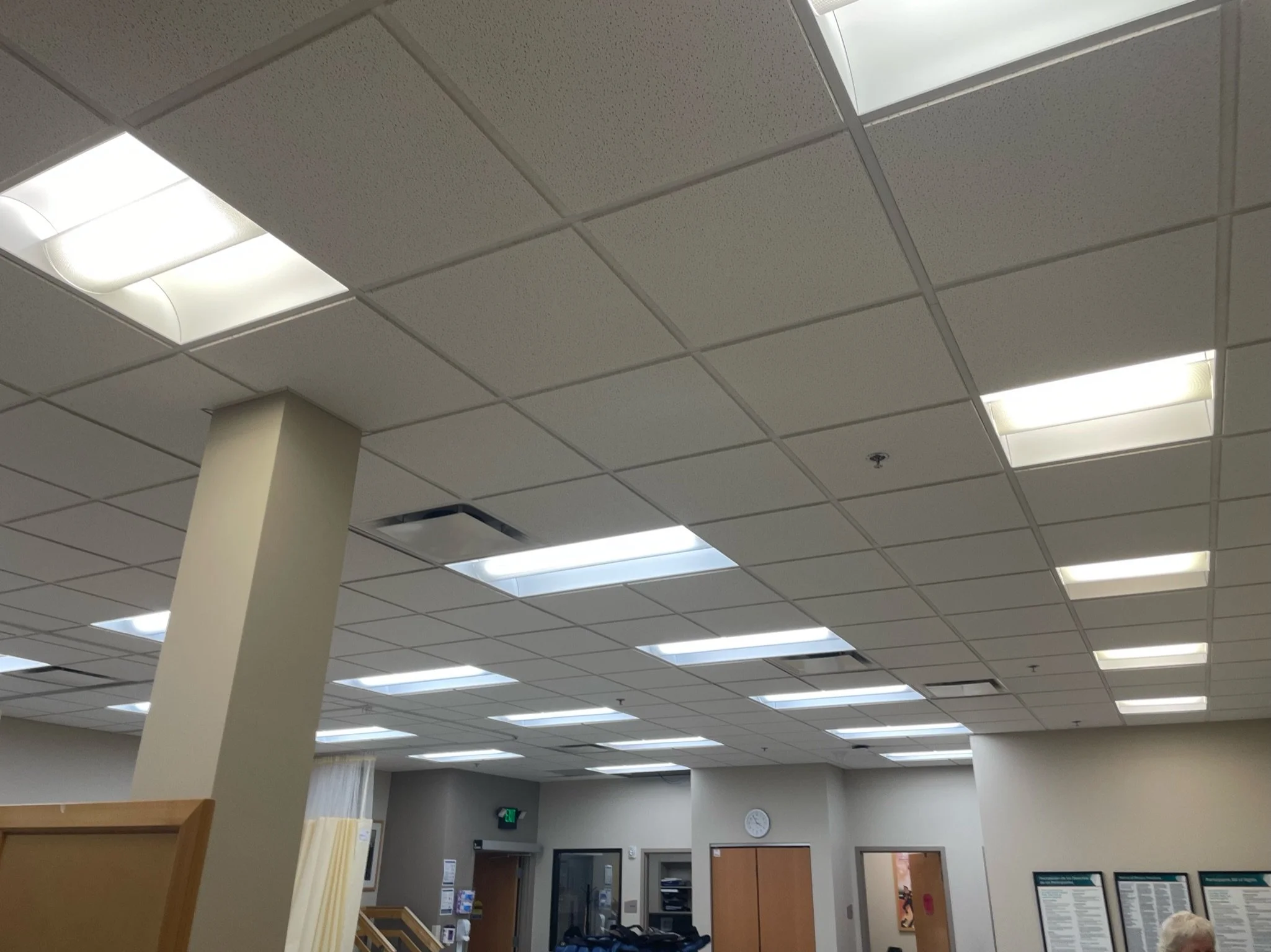 Ceiling of an indoor space with grid of acoustic tiles and fluorescent light fixtures.