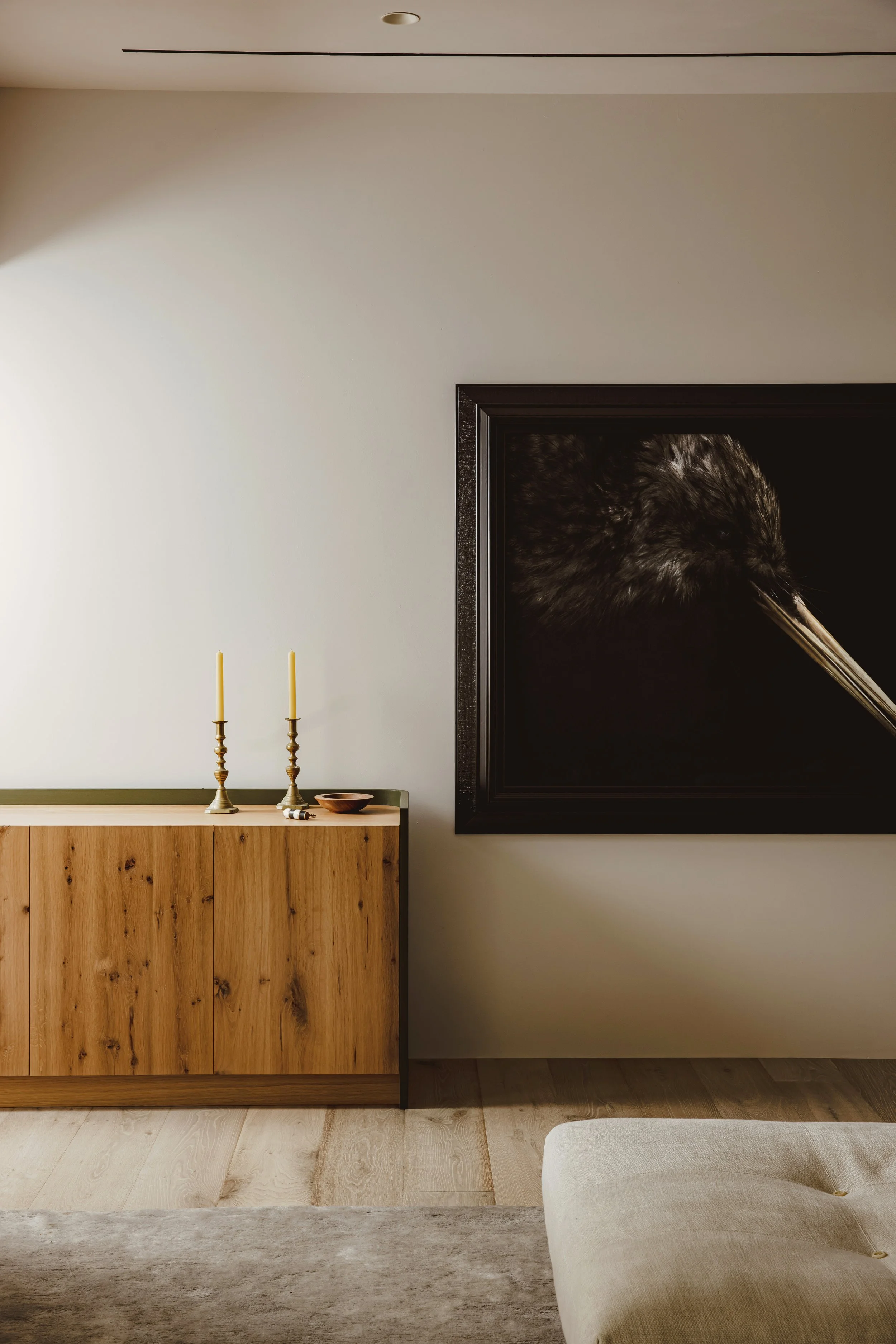 Modern living room with wooden sideboard, two candlesticks, a decorative bowl, and framed artwork on the wall.