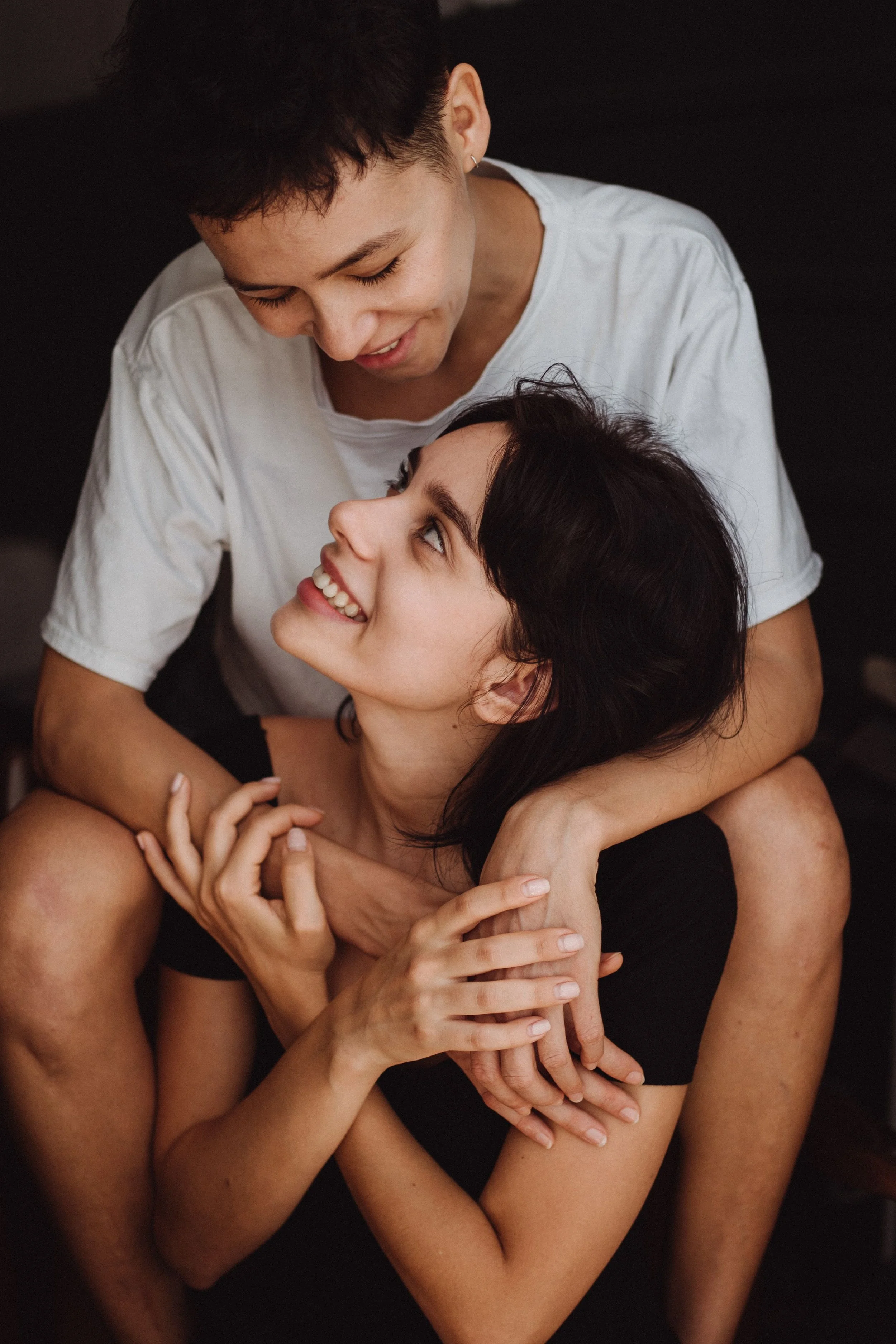 Two queer people embrace each other affectionately.