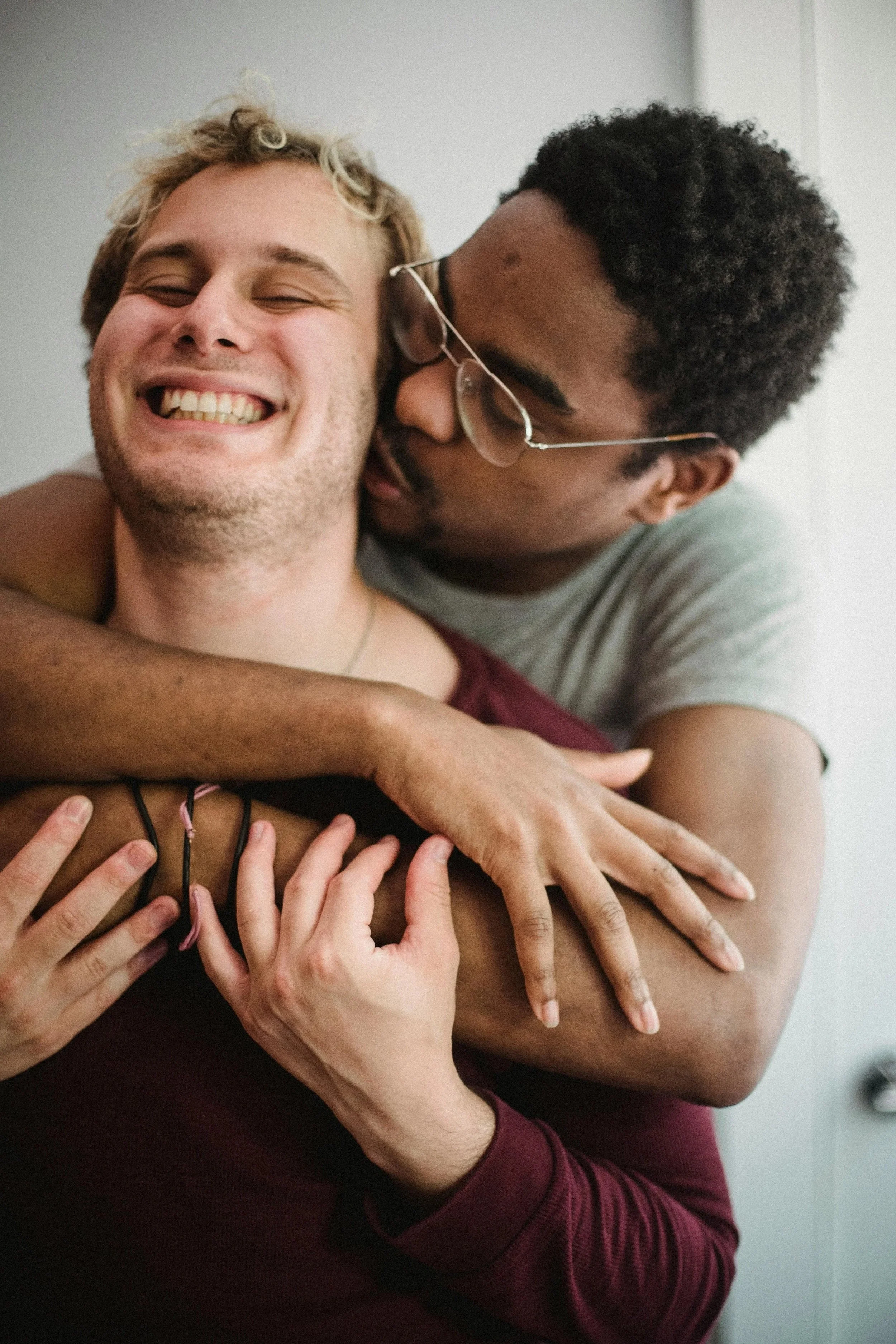 Close-up of two LGBTQIA+ people hugging, representing belonging, connection and safety through online therapy in North Carolina and South Carolina.