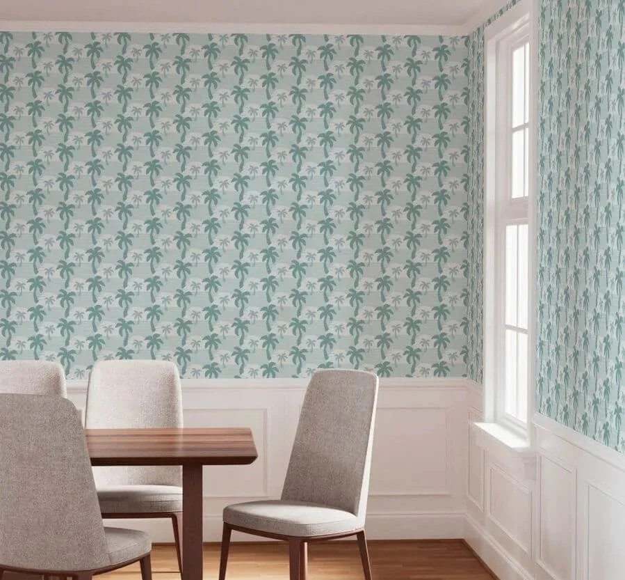 A room with tropical palm tree peel and stick wallpaper, a window, wood floor, and partial view of a wooden table with beige upholstered chairs.