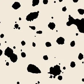 Loose, inky splashes and dots in black are scattered across a butter cream ground, creating an abstract, organic, allover “ink splatter” look that feels modern, playful, and slightly stone-like.