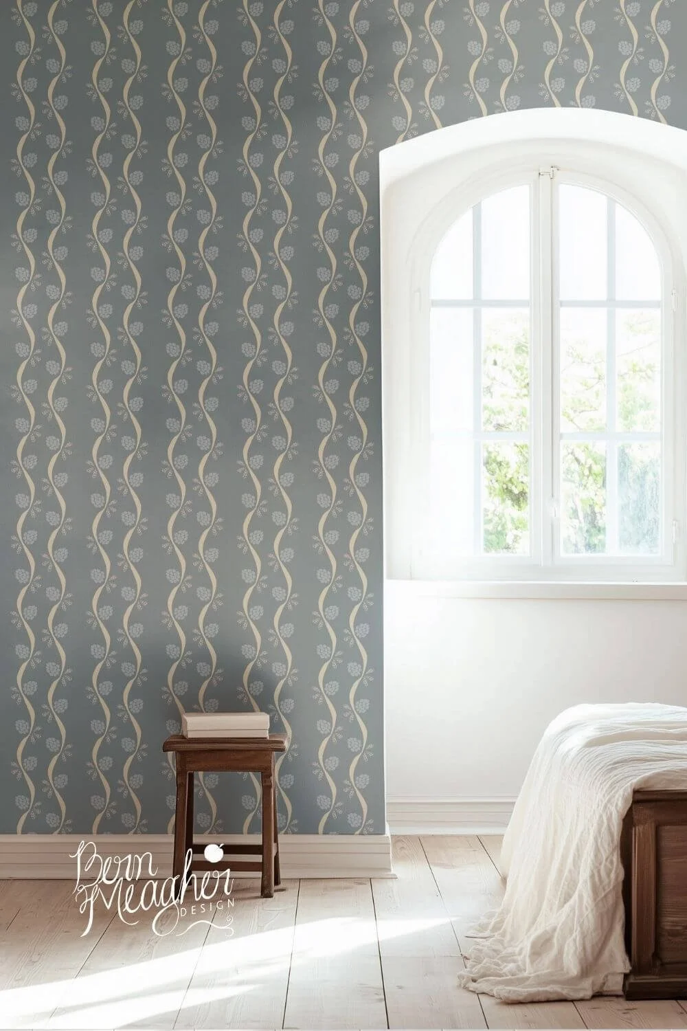 Blue and cream peel & stick wallpaper with vertical wavy stripes and small floral elements in a bright bedroom setting featuring light wood floors, a wooden stool with books, and a white bedspread near a large window.