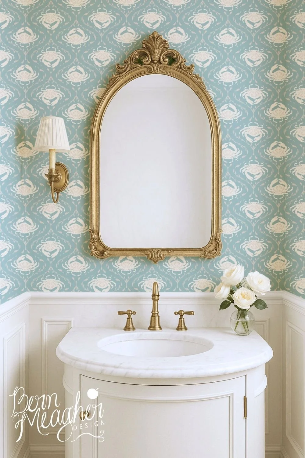Blue seafoam traditional wallpaper with repeating cream crab pattern in a coastal-inspired bathroom featuring a white marble sink, gold faucet and mirror, and a wall sconce.