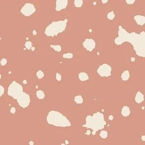 Loose, inky splashes and dots in yellow cream are scattered across an earthy clay ground, creating an abstract, organic, allover “ink splatter” look that feels modern, playful, and slightly stone-like.