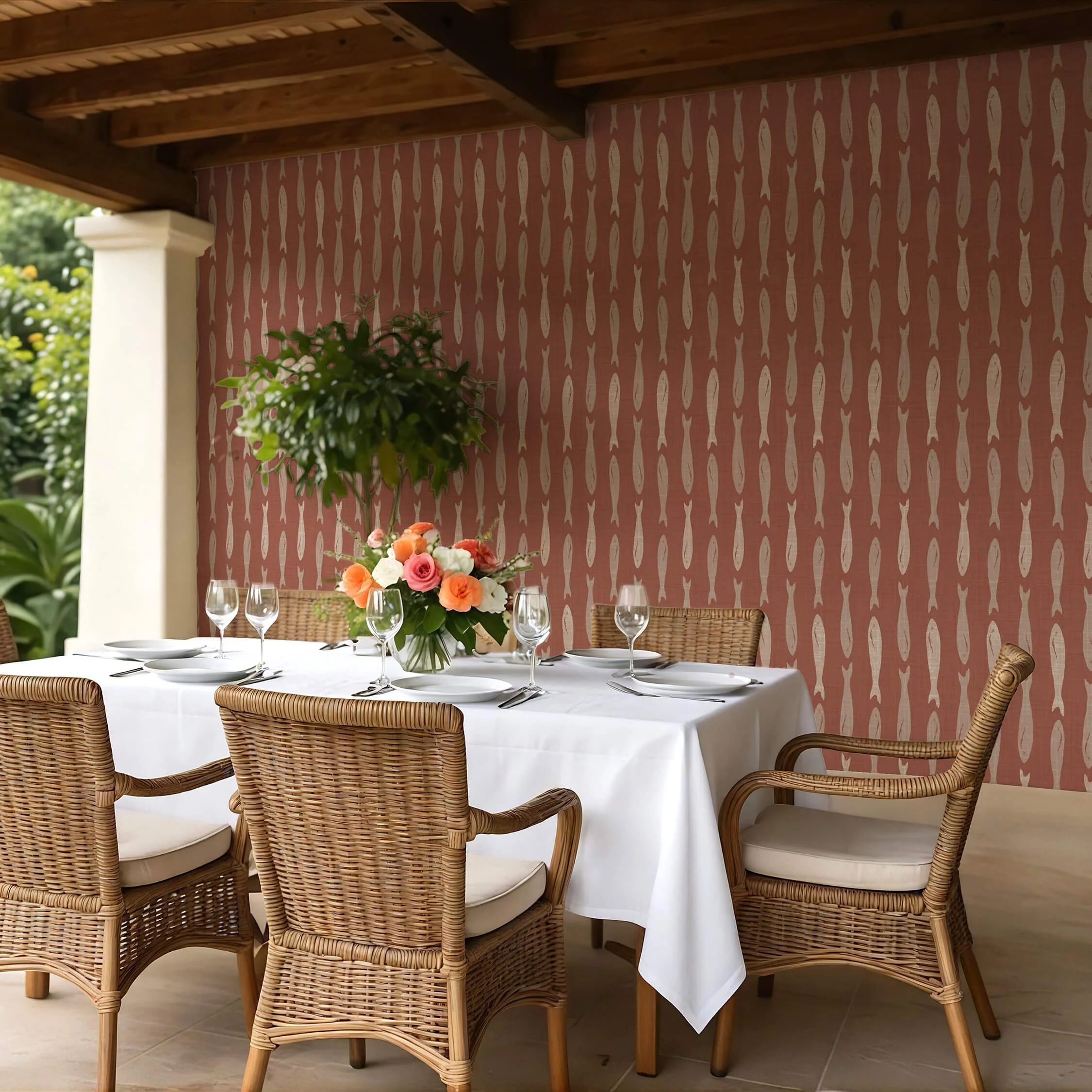 Peel and stick wallpaper in warm terracotta with a repeating sardine fish pattern, styled in an outdoor dining area featuring natural wicker chairs, a white tablecloth, and floral centerpiece under a wooden pergola.