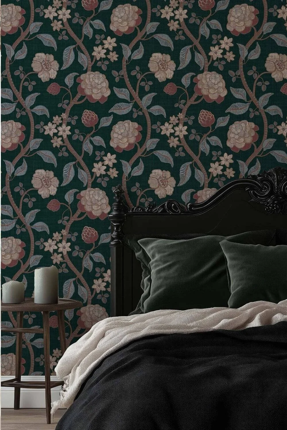 Dark teal Victorian-style peel and stick wallpaper featuring intricate floral and leafy patterns displayed behind a black ornate bed with dark teal velvet pillows and neutral bedding, alongside a wooden side table holding candles.