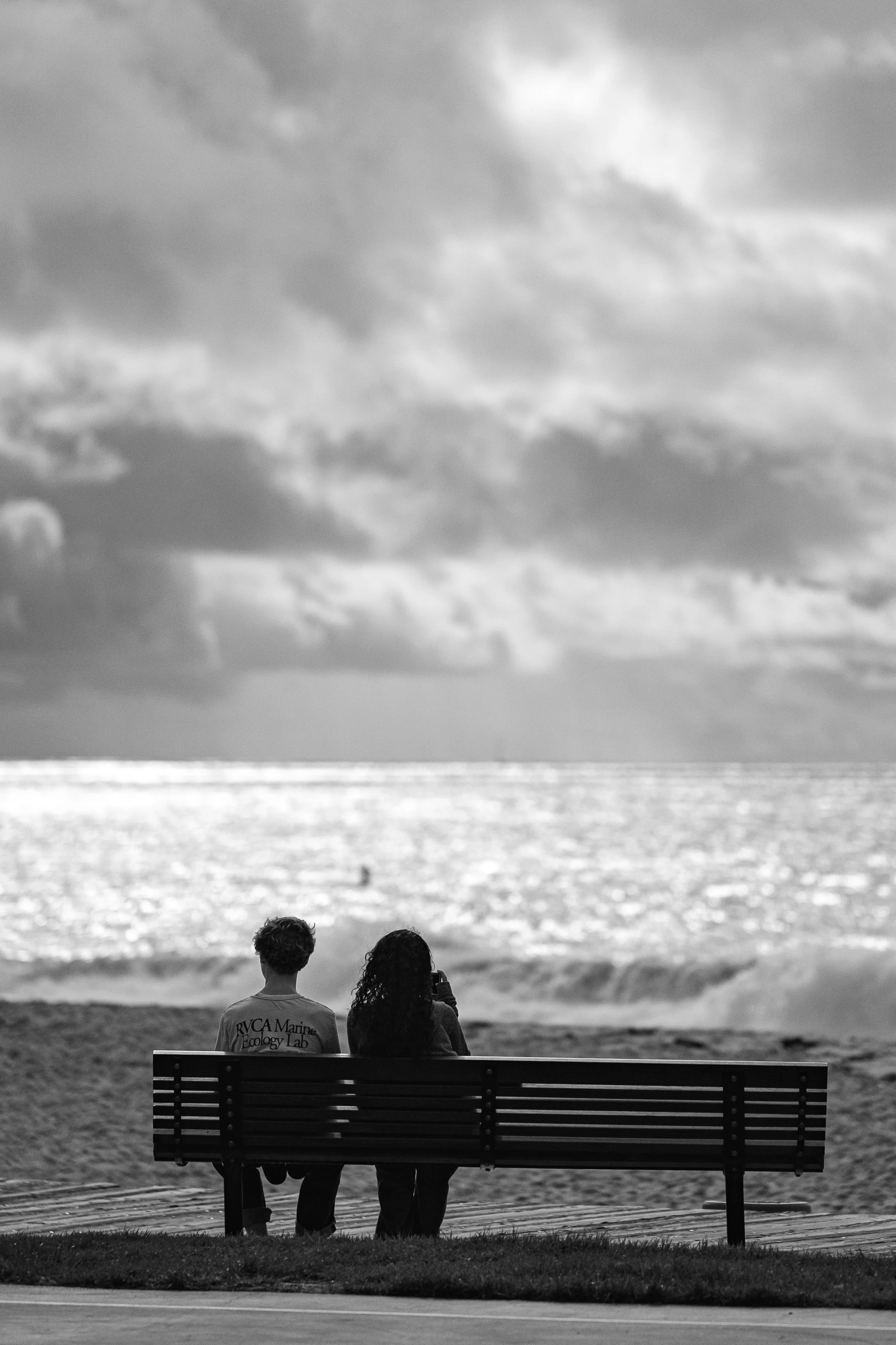  A black-and-white study of a couple witnessing the scale of the Pacific, emphasizing texture and light. 