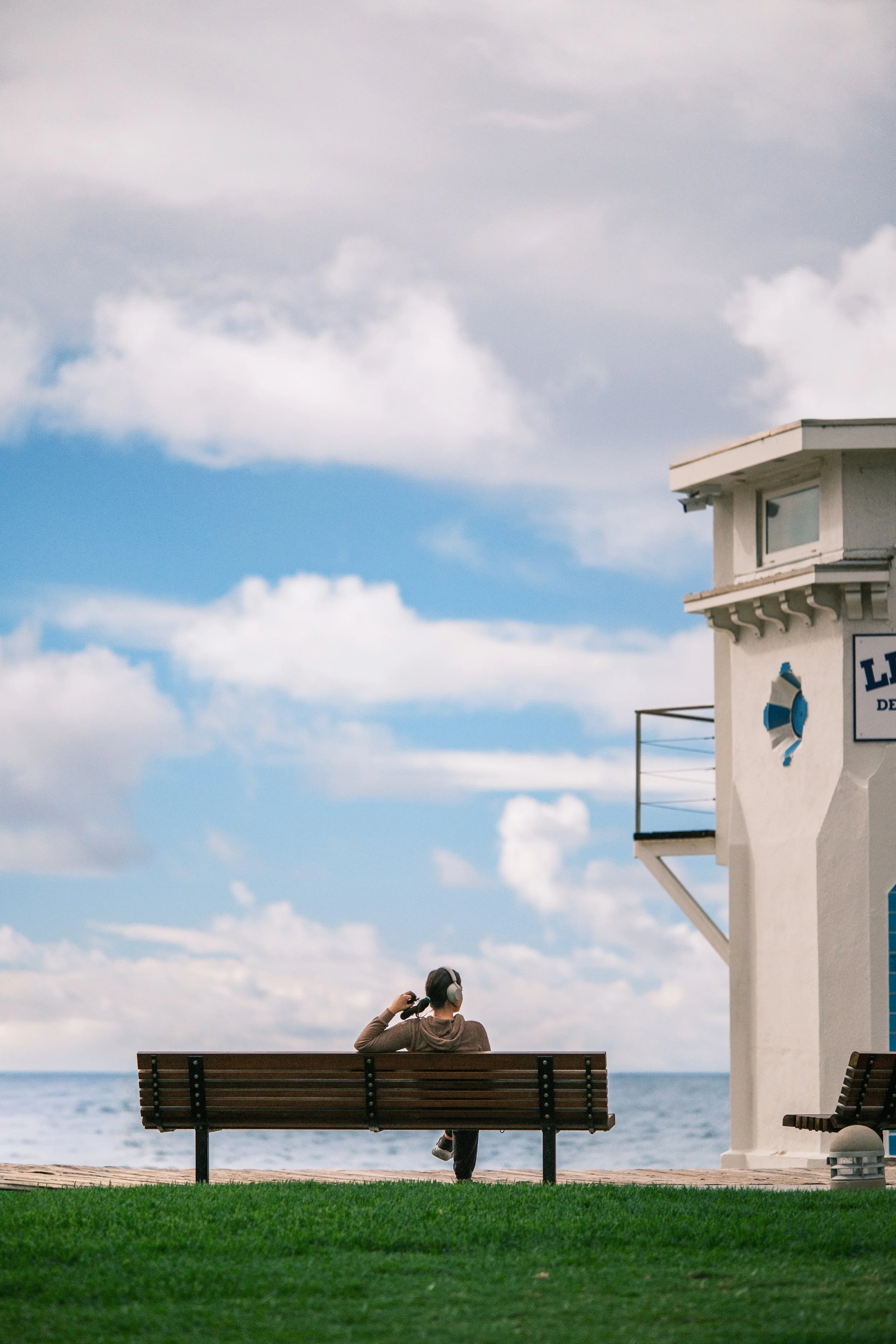  A candid study of solitude; a girl fiddling with her hair and listening to music beside the Main Beach Lifeguard Tower. 