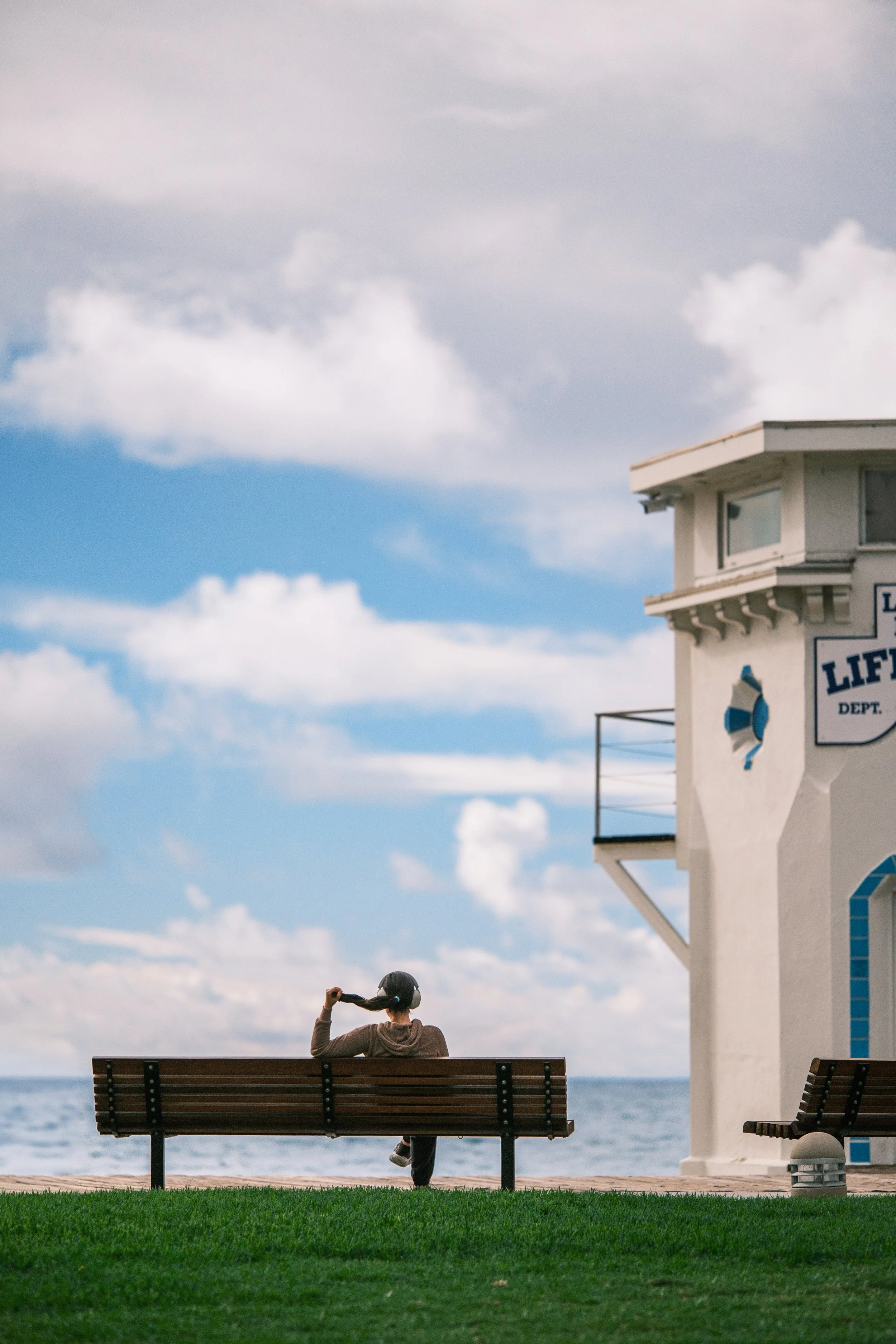 A candid study of solitude; a girl fiddling with her hair and listening to music beside the Main Beach Lifeguard Tower.