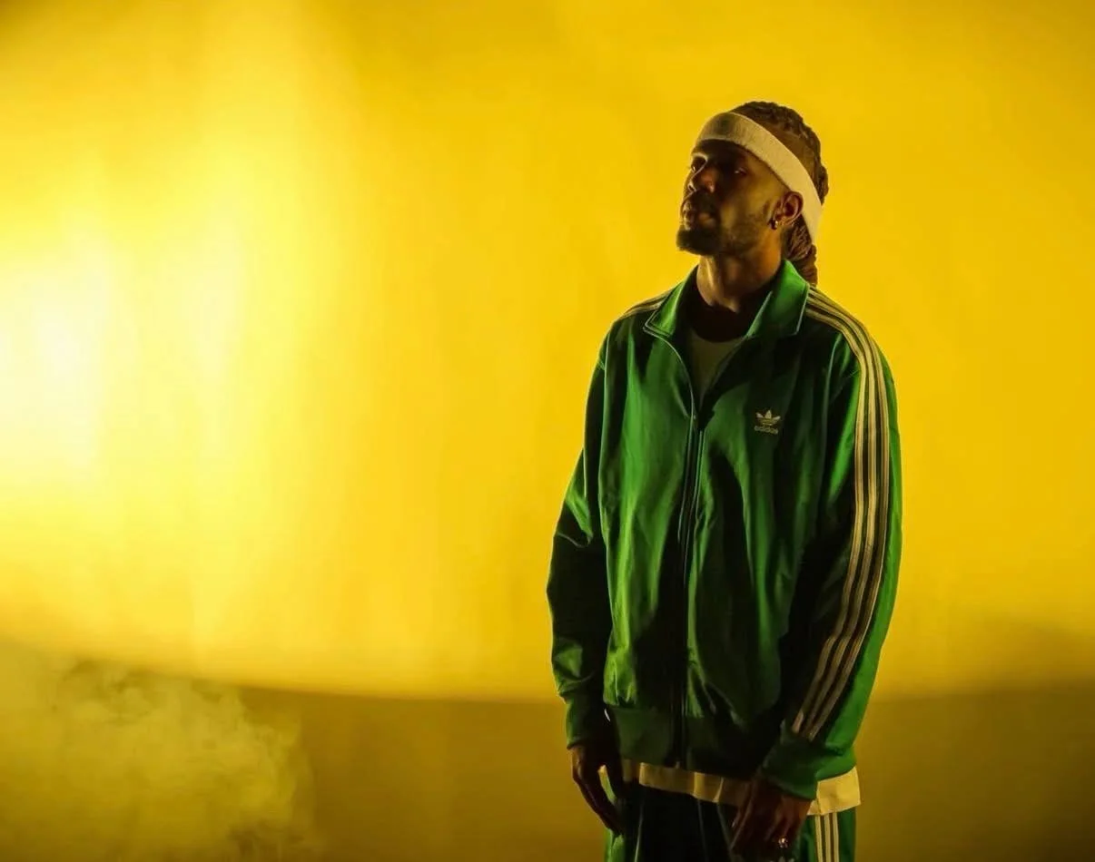 USDD founder Lexi Maize in a green tracksuit against a yellow wall.