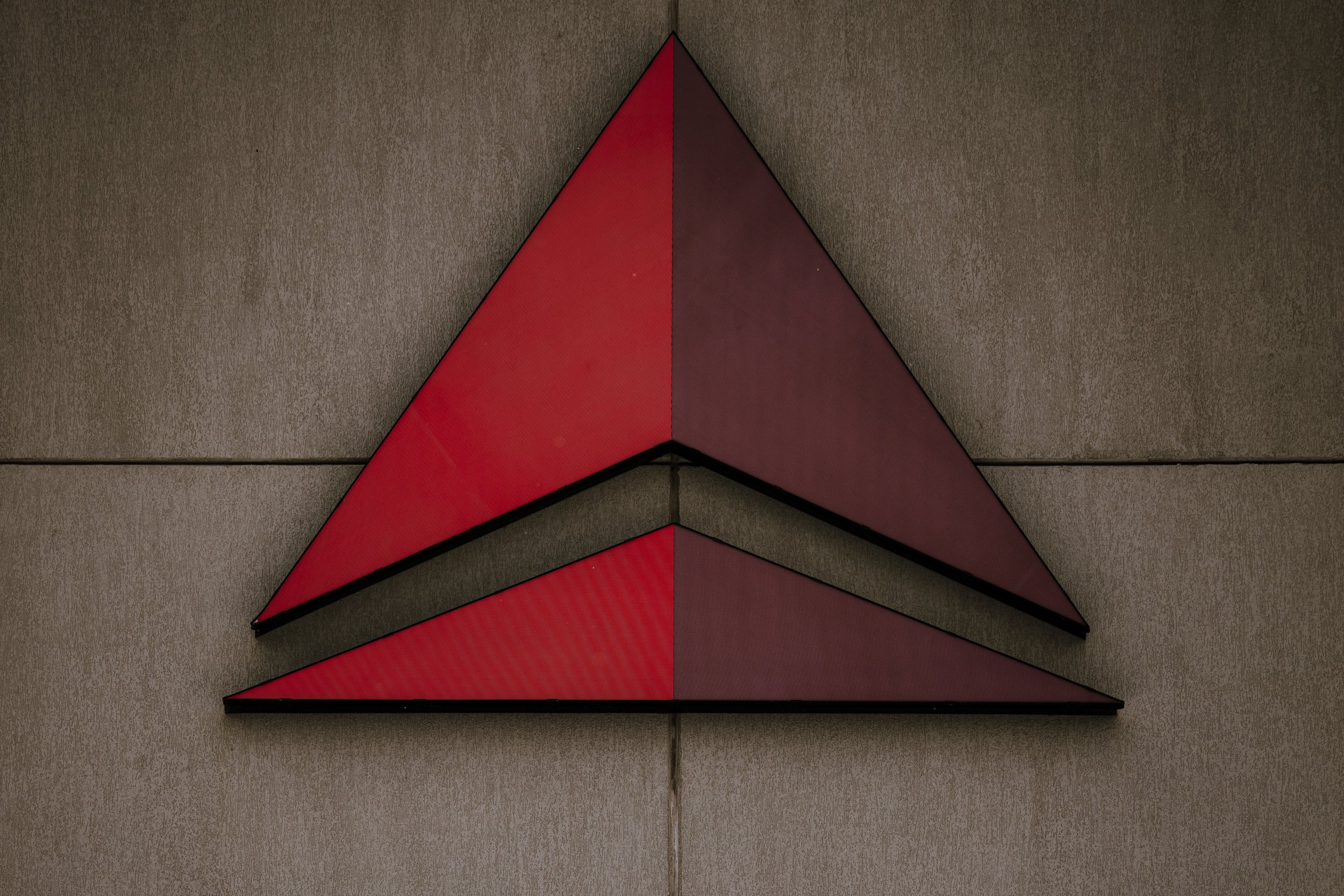 A metallic sign with two large, painted red arrow shapes mounted on a beige wall.