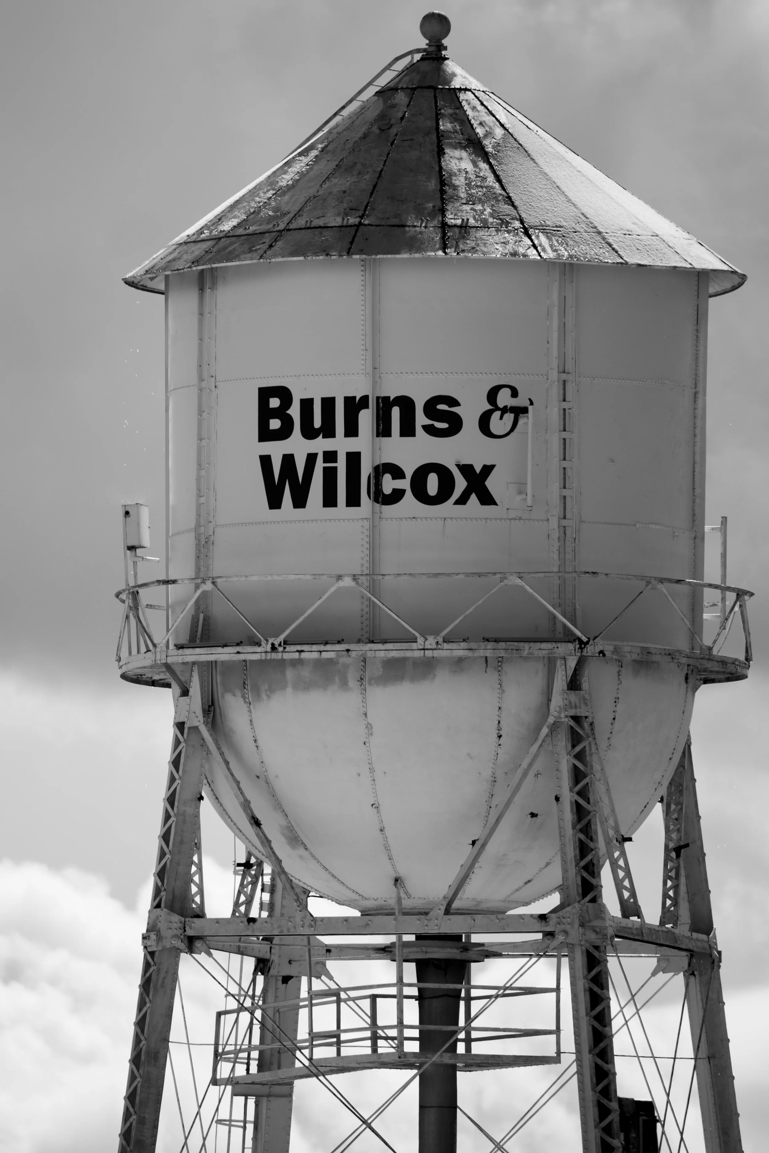 An old water tower with the words 'Burns & Wilcox' painted on it in bold black letters.