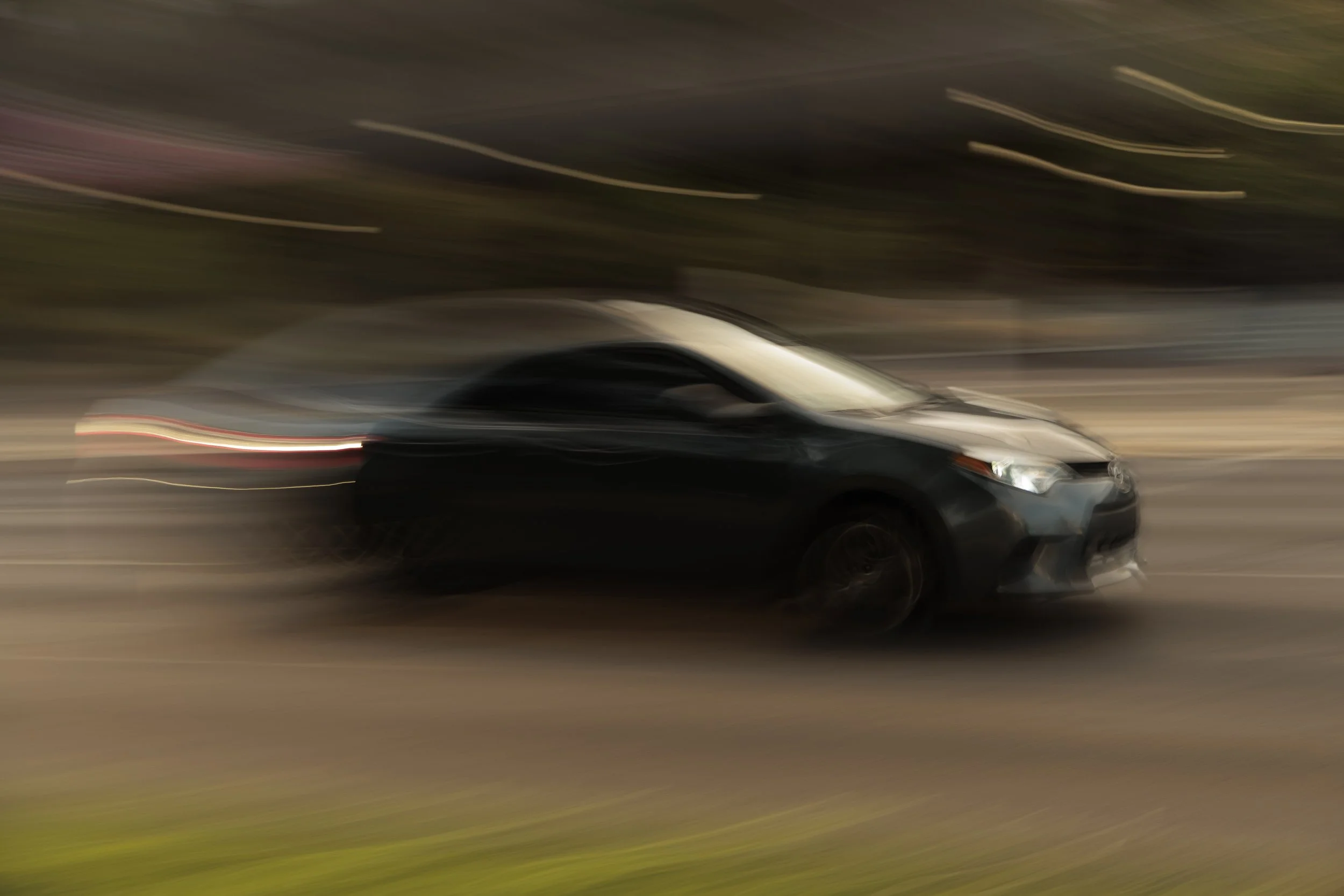 A black car moving at high speed on a road, creating a motion blur effect