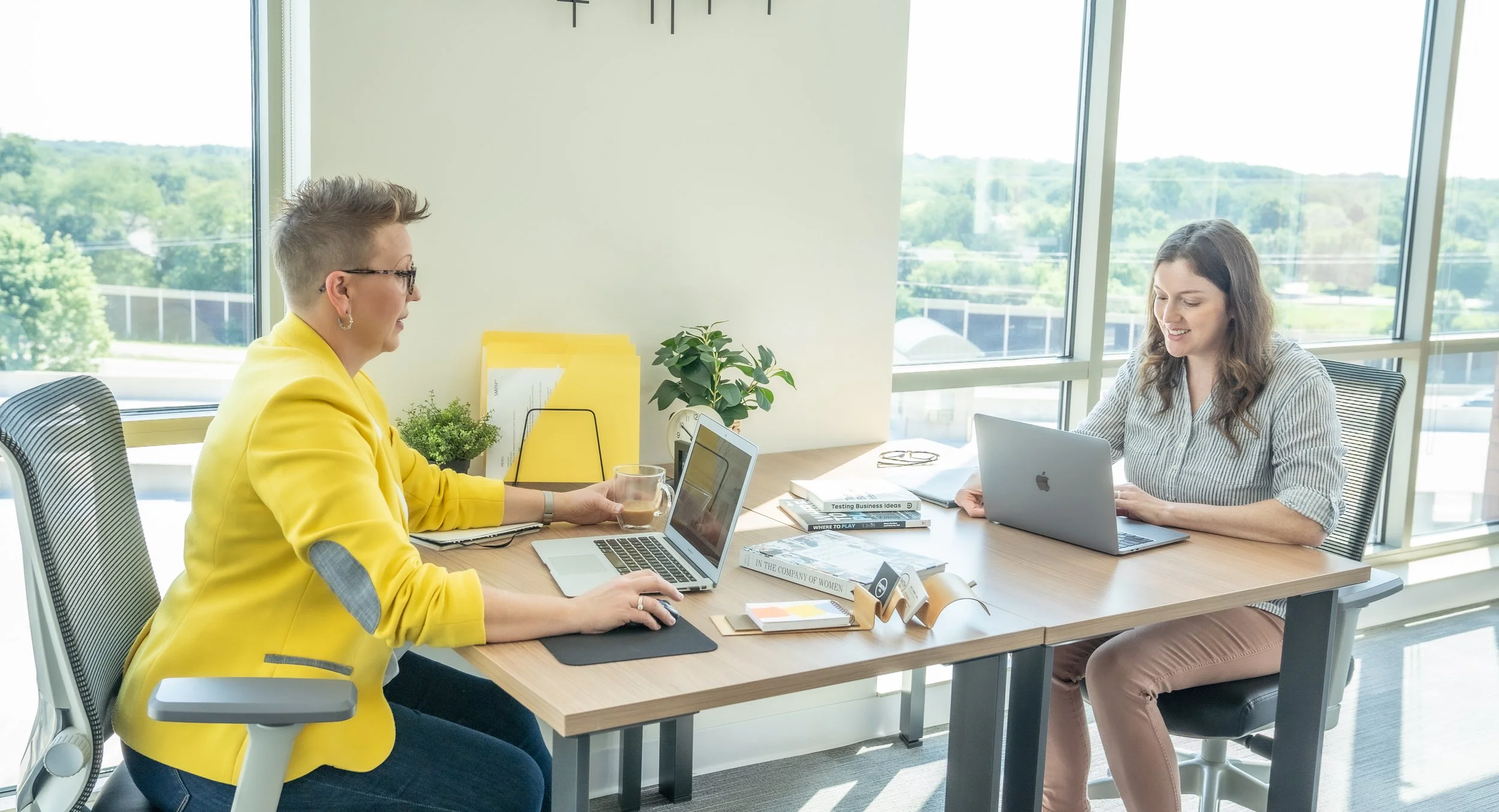 Two women collaborating at a desk in an office discussing B2B sales coaching.