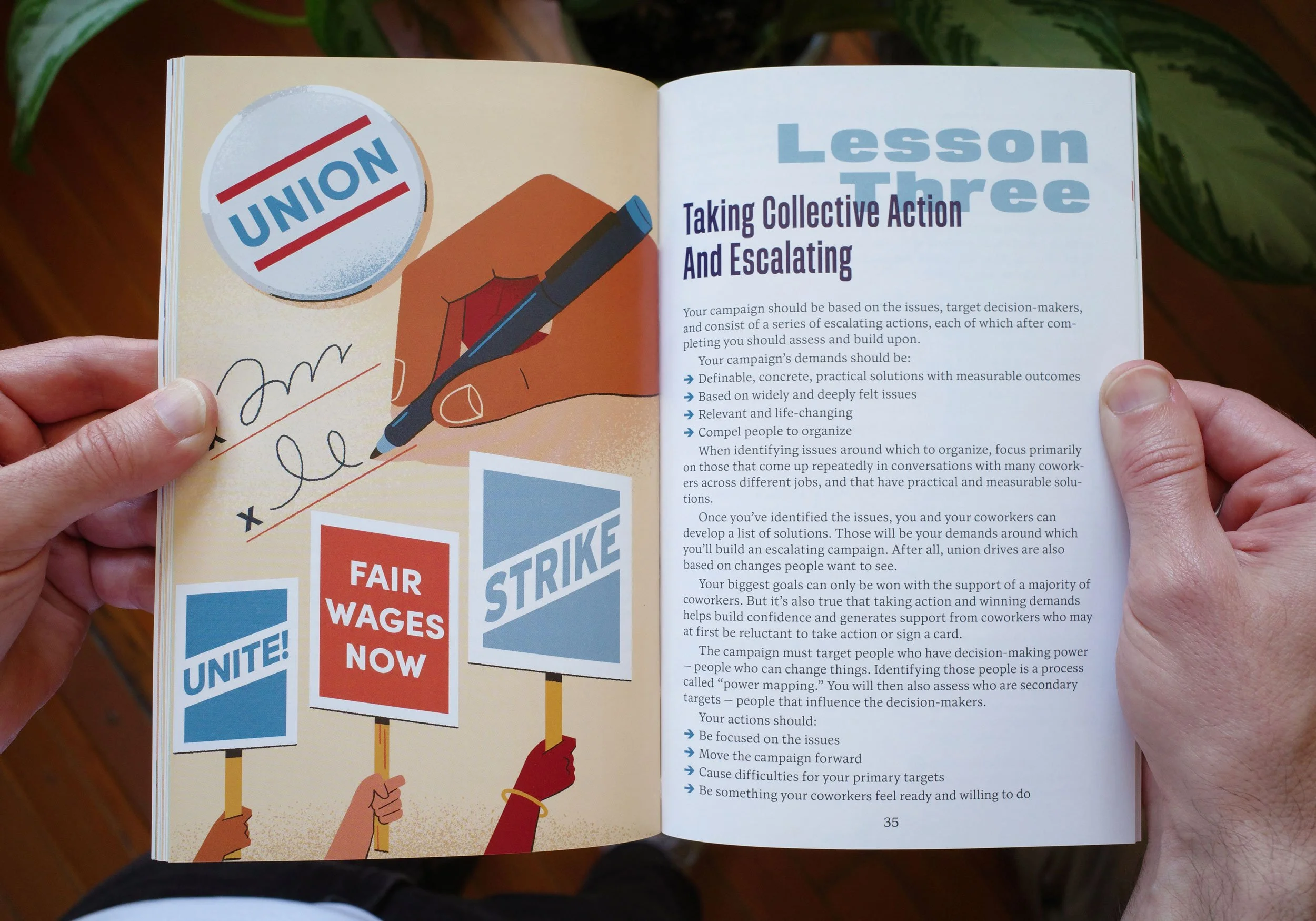Open book with illustrations of protest signs that read "UNITE!", "FAIR WAGES NOW," and "STRIKE" alongside a hand signing a signature, with text discussing union activities and collective action.