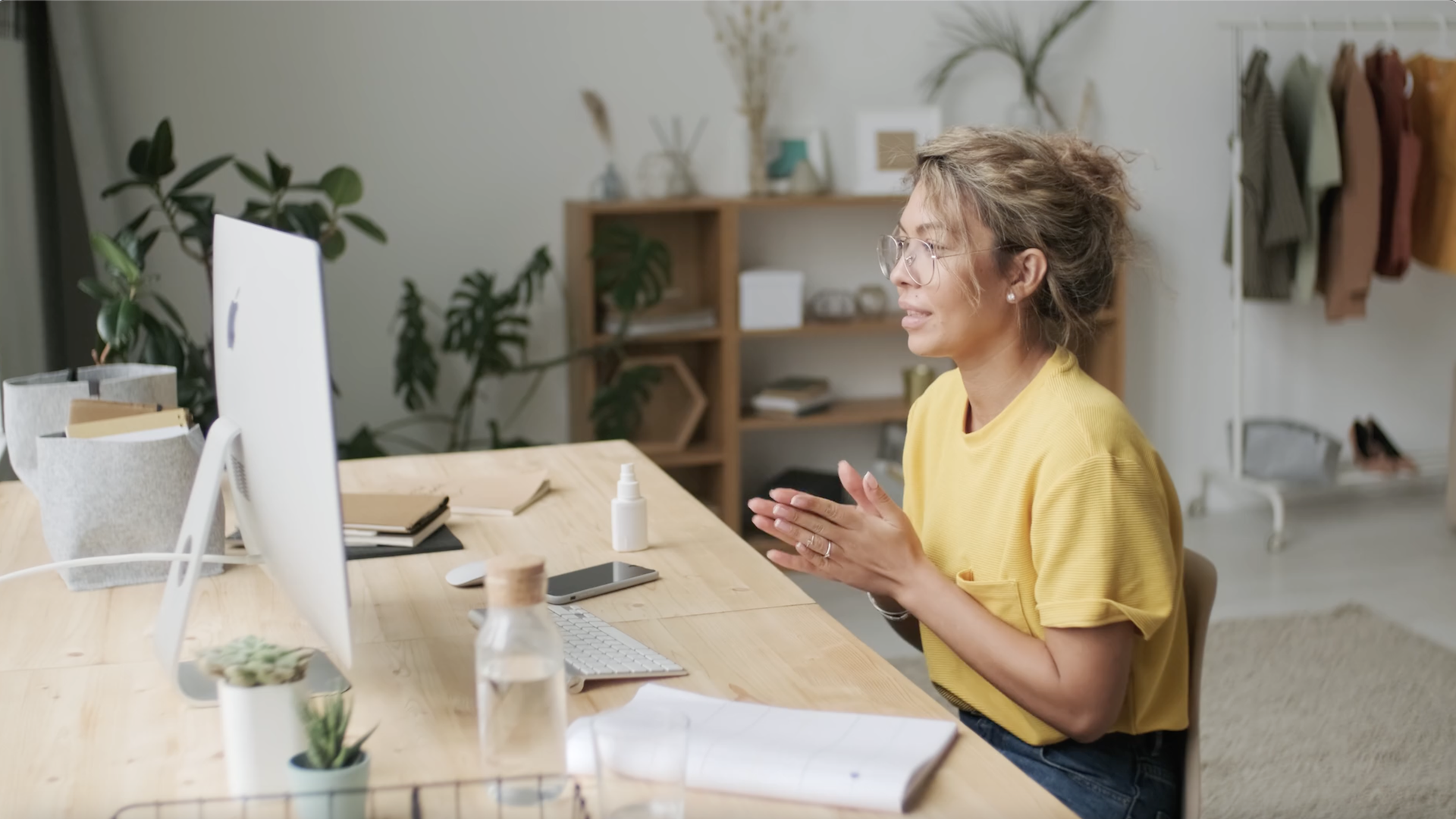 Woman in yellow shirt talking to someone on video call at her home office