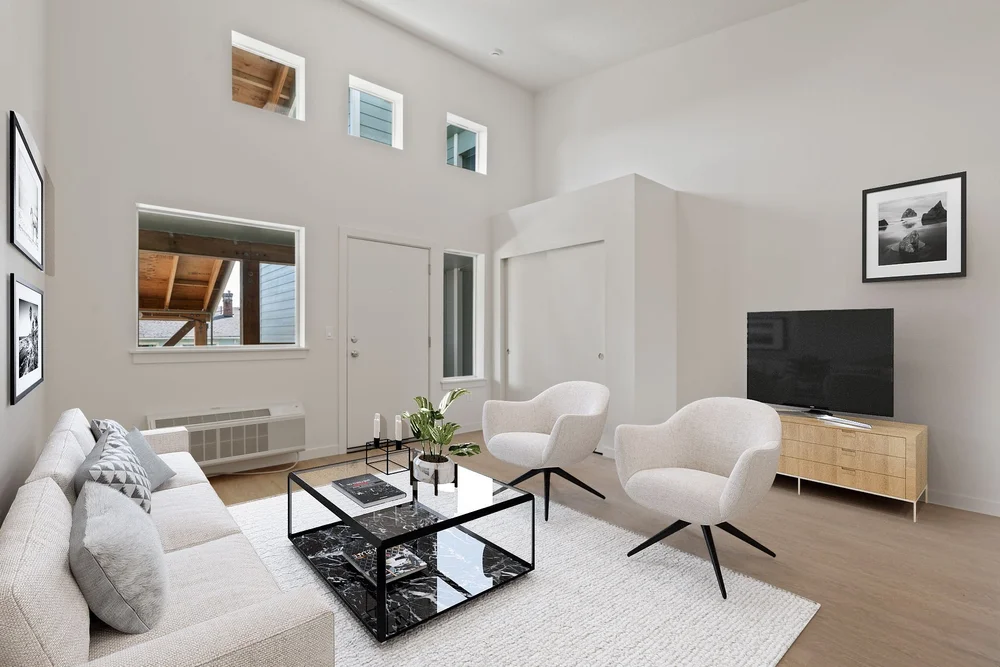 Furnished living room with large windows and white walls