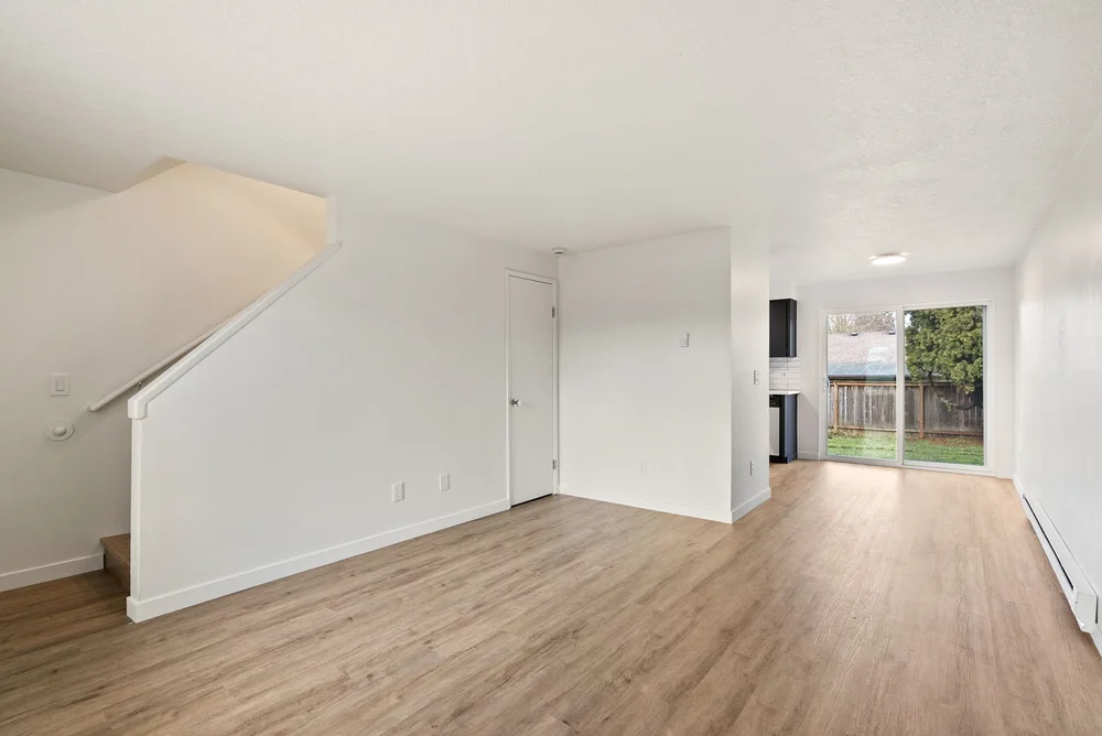 Renovated living room with light wood-look flooring and a sliding door to the patio