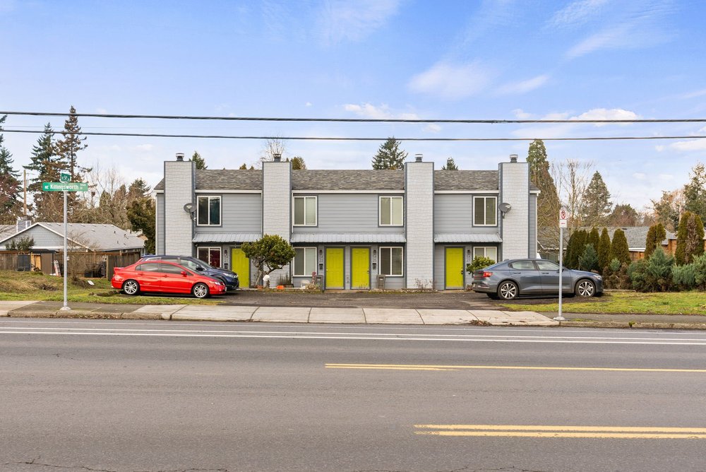 The full building from across NE Killingsworth, with four yellow doors and parking in front