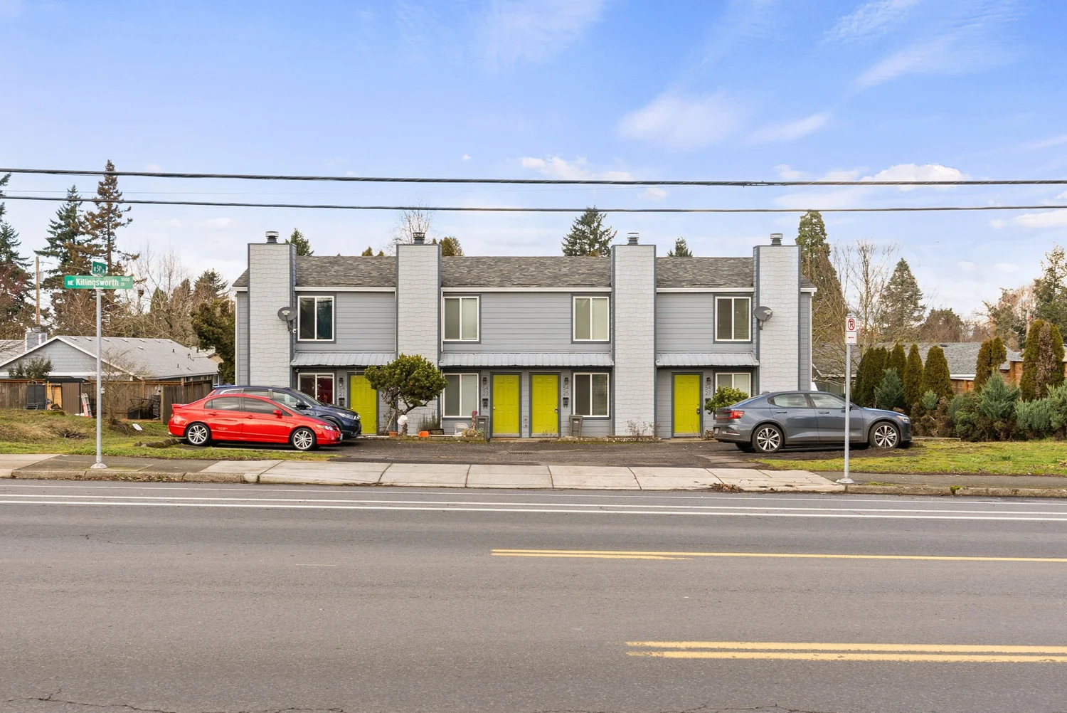Gray two-story apartment row with bright yellow front doors along NE Killingsworth
