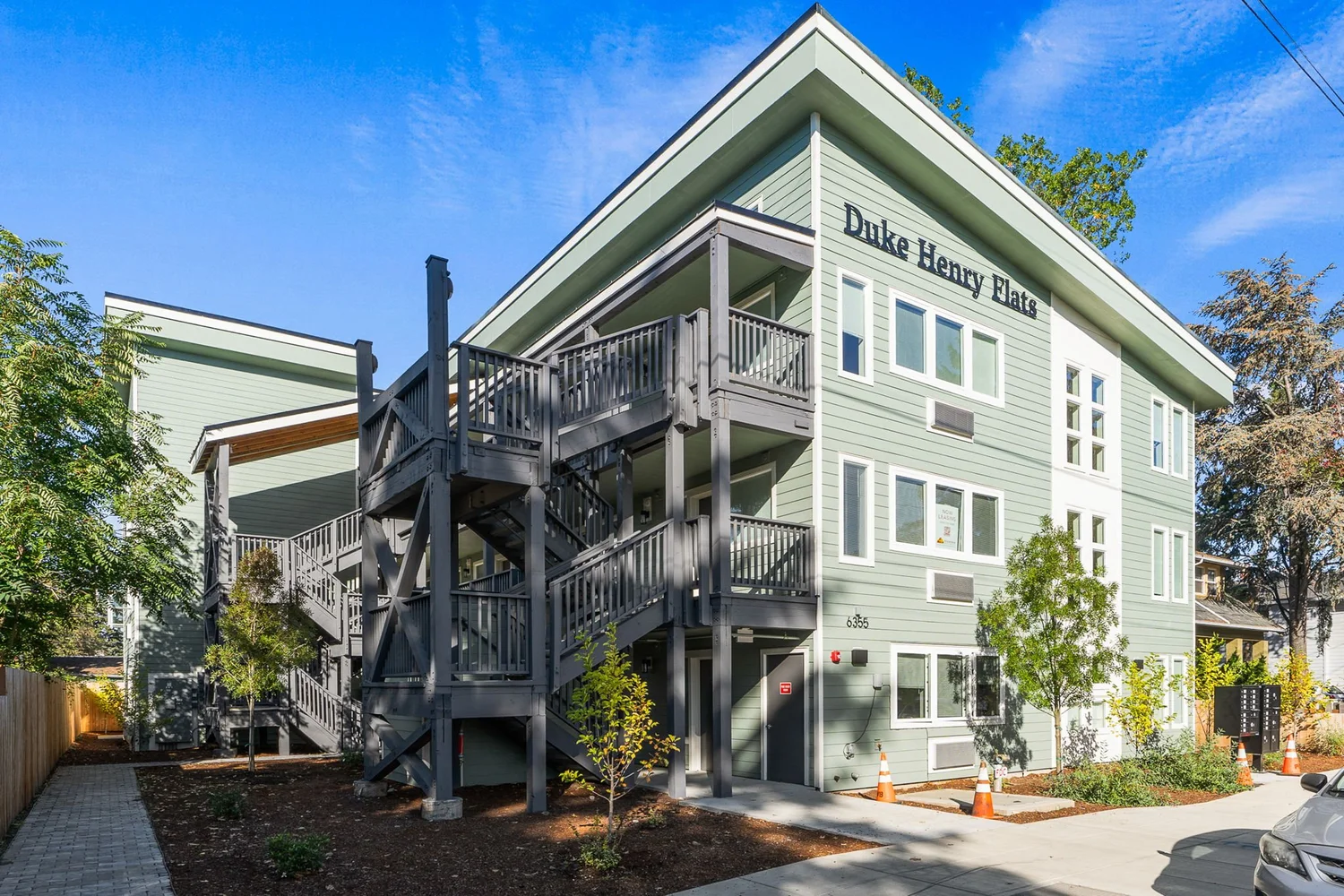 Three-story apartment building with green siding and timber stairs