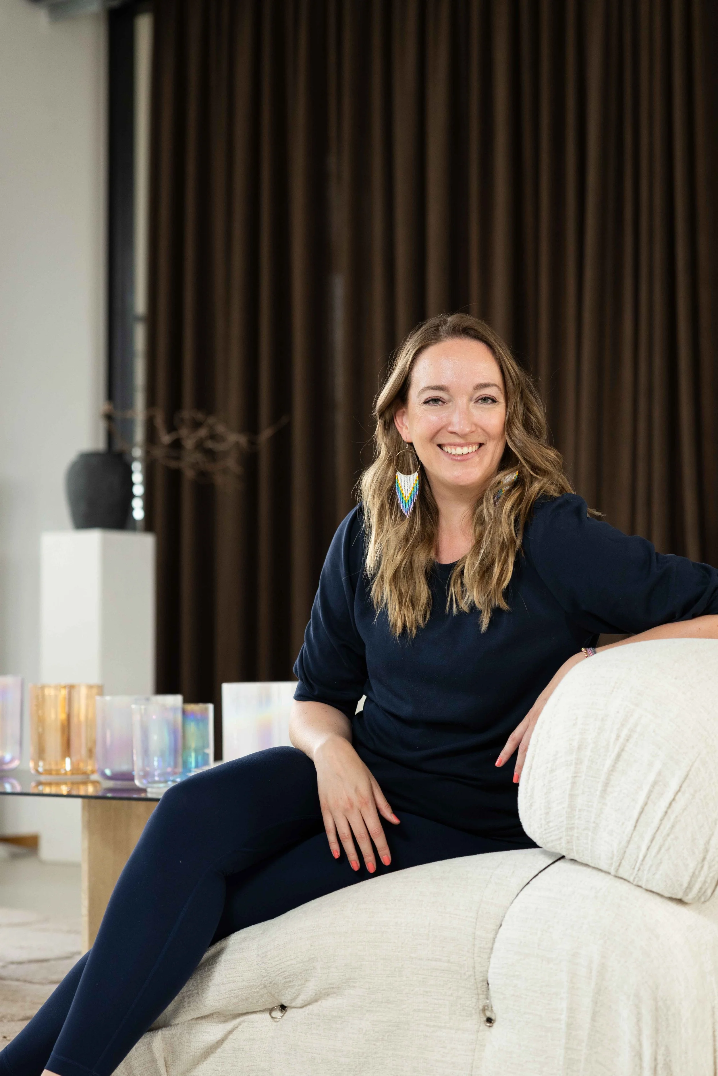 "Sound & Silence" Gründerin Annika List sitzt auf einem hellen Sofa vor ihrer Kristallklangschalen-Marke.