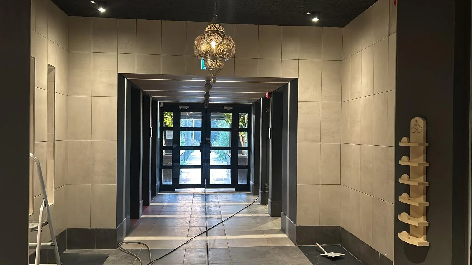 Een smalle gang in een modern gebouw met witte en marmeren wanden en zwarte en witte tegelvloer.