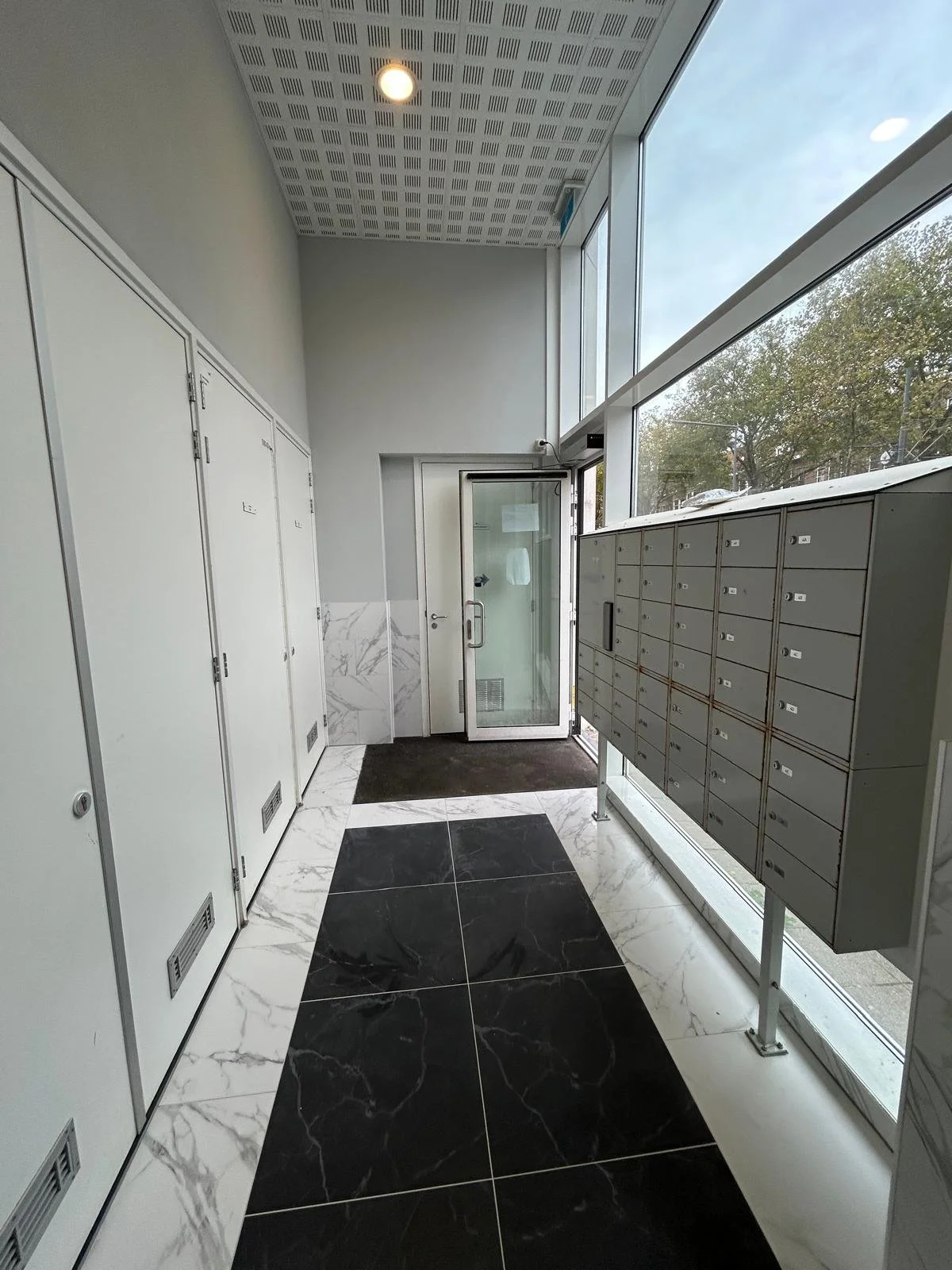 Binnenkant van een moderne postkantoor of gemeenschappelijke brievenbus ruimte met kozijnen, postvakjes en een deur.