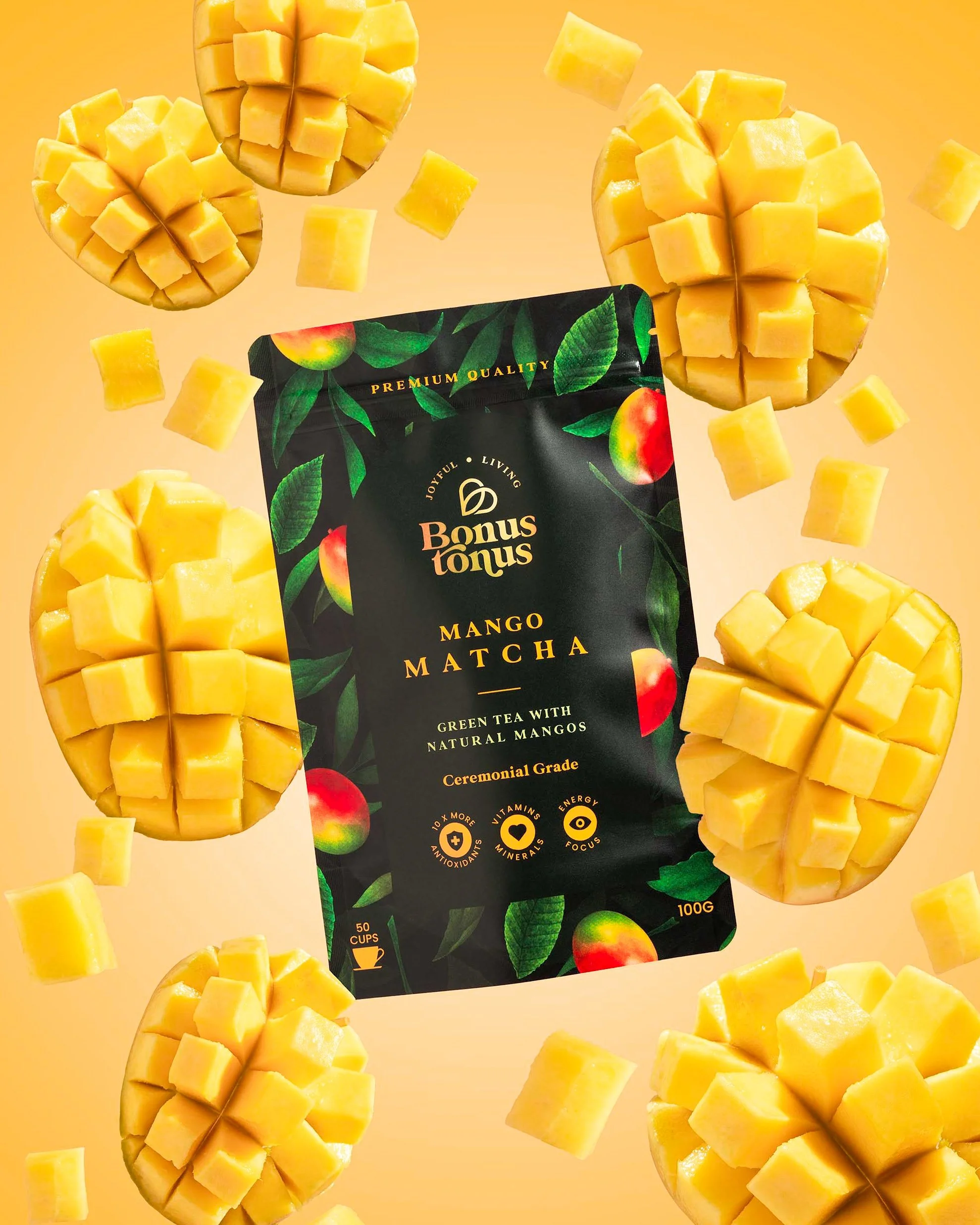 Package of Bonus Tonus Mango Matcha green tea with natural mangoes surrounded by sliced and cubed fresh mangoes against a yellow background.