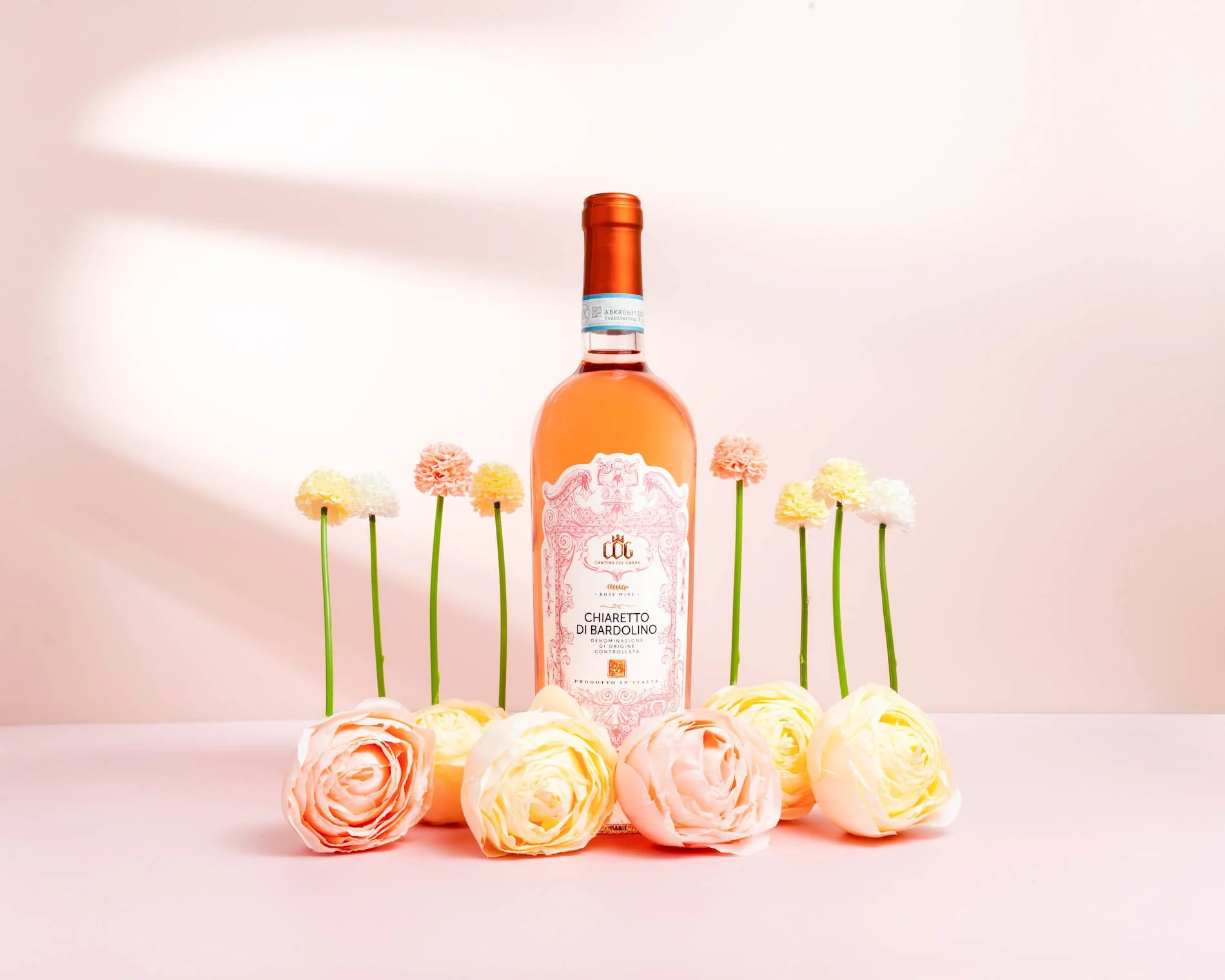 Bottle of Chiaretto di Bardolino rosé wine surrounded by pastel-colored flowers.