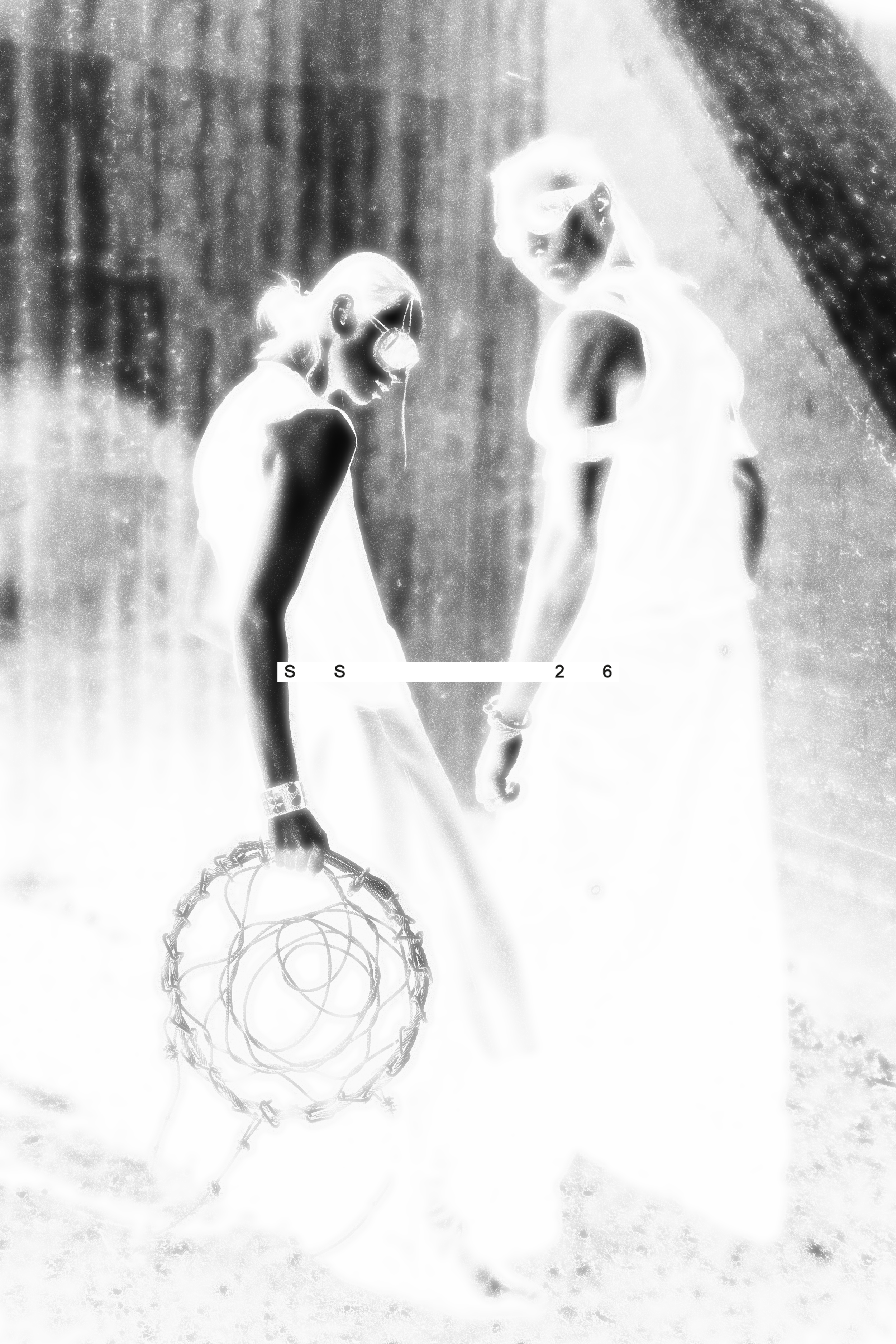 Black and white photo of two models, one holding a large metal dreamcatcher, both wearing sunglasses and avant-garde clothing, standing in a brutalistic environment. Daniel Alexander Weiter - DAW