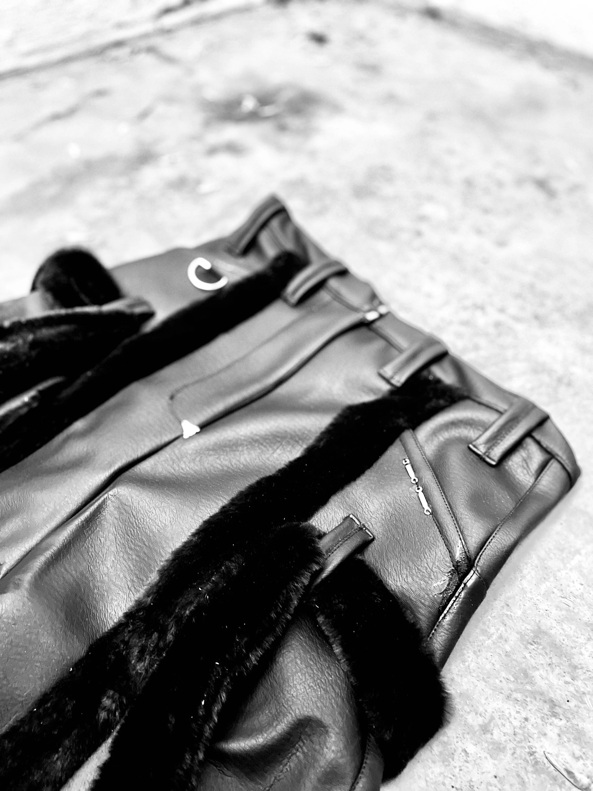 A pair of black leather pants on a concrete floor, with short pile fur accents. Pnther Pants Daniel Alexander Weiter - DAW