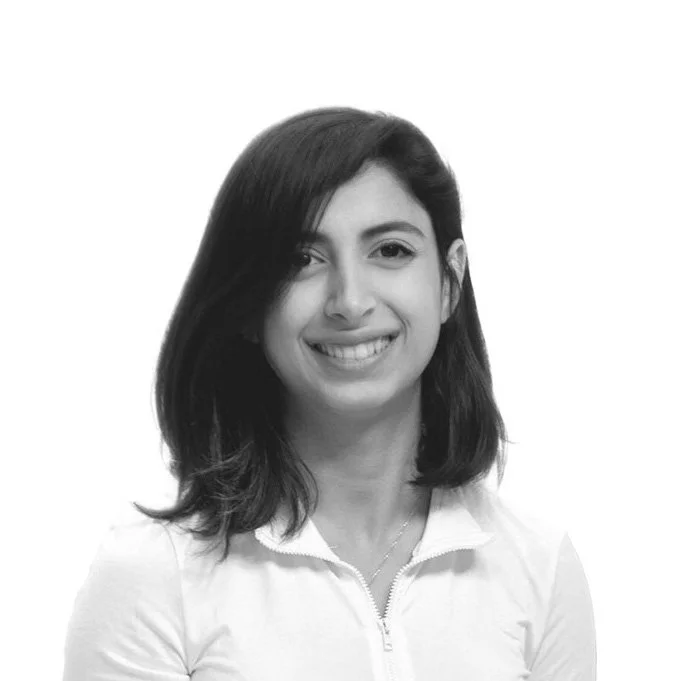 Black and white portrait of a woman with shoulder-length hair, smiling and wearing a zippered jacket.