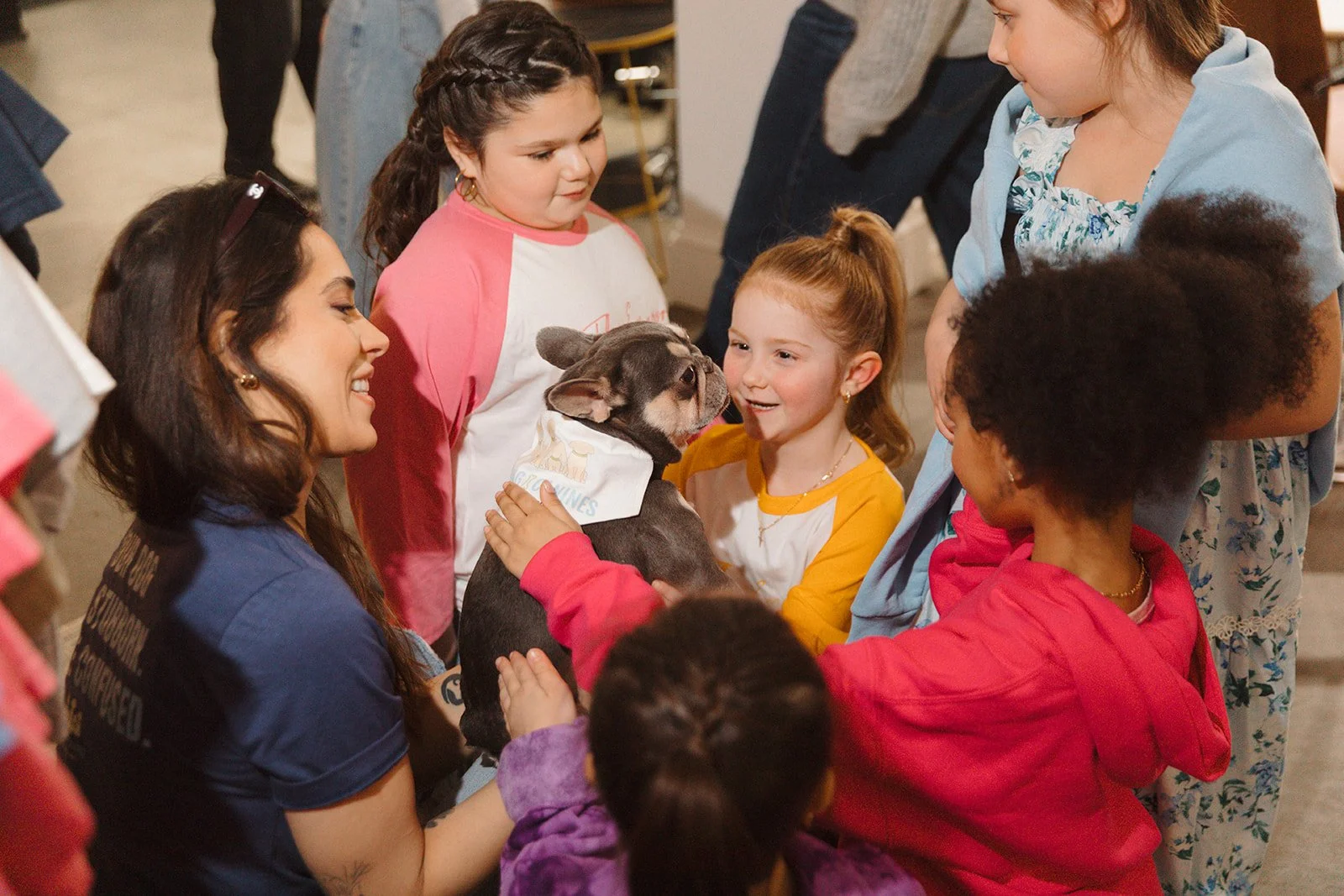 A woman presenting a well trained Frenchie to a group of people. The dog is calm and non reactive to large groups.