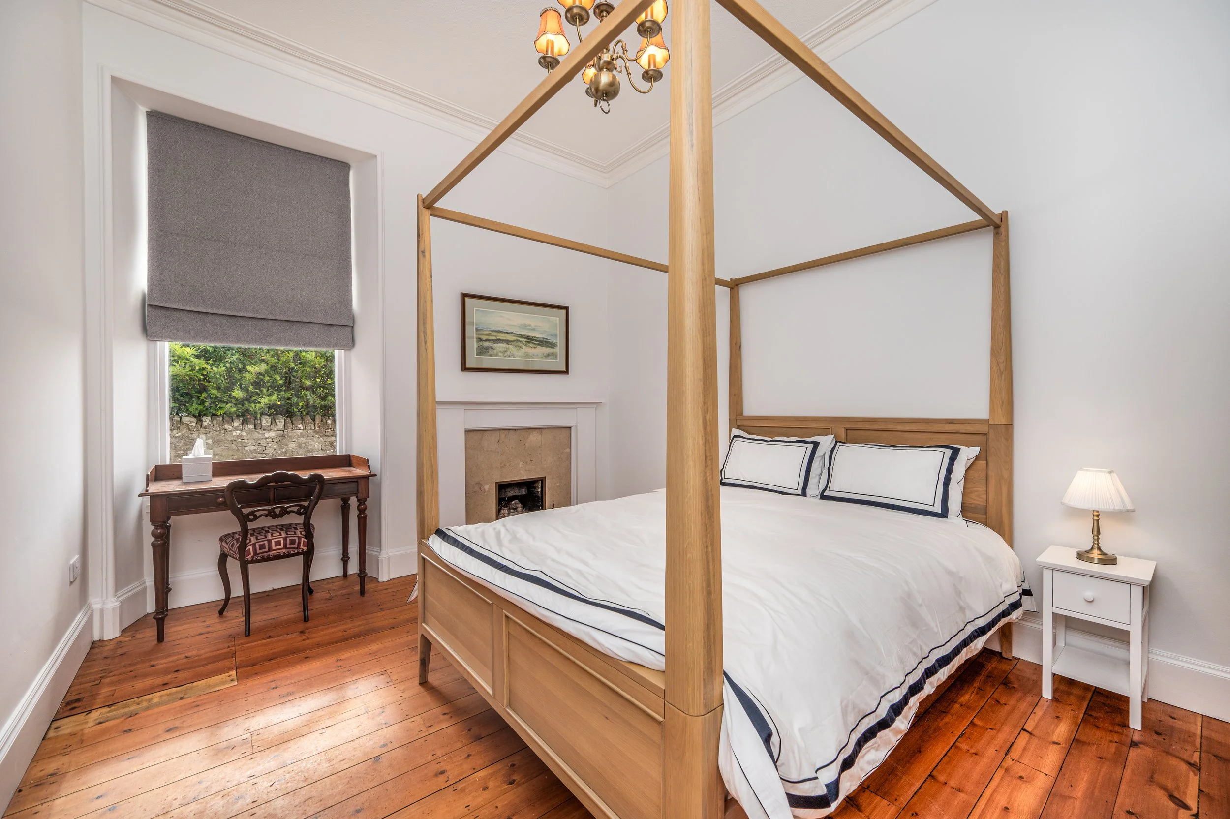 Modern bedroom with double bed, plaid bedding, glass doors, and wooden furniture.