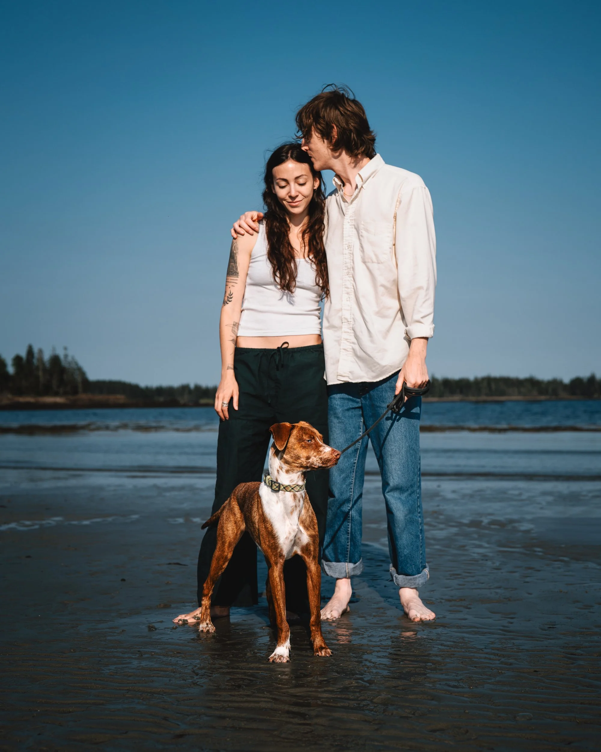 Emilie and Greg standing with Beso on Crescent Beach in Owls Head, Maine